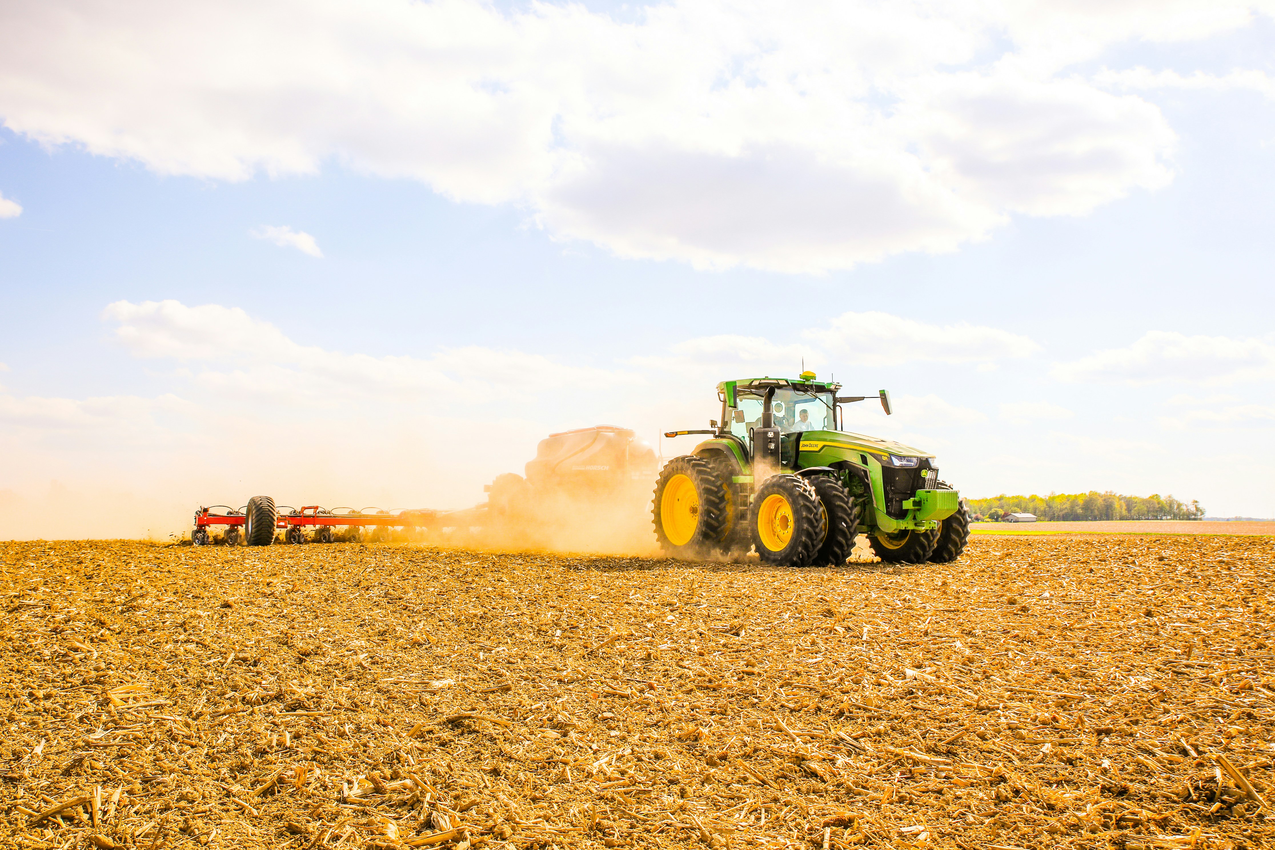 a tractor is plowing a field with a trailer