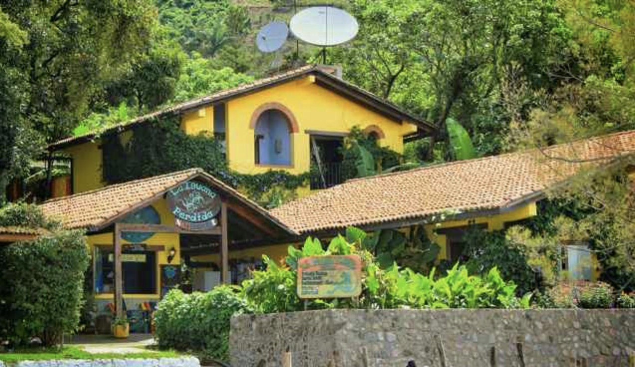 Bright yellow multi-level building with a tiled roof surrounded by trees.
