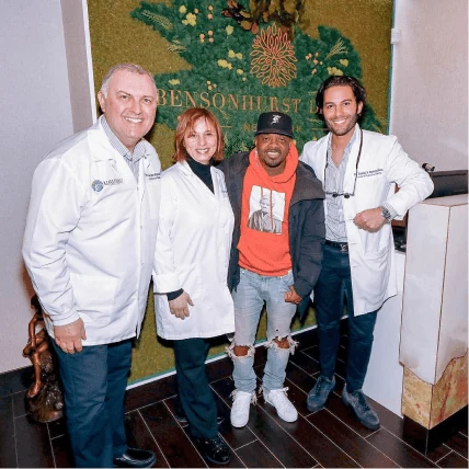 Music producer Jermaine Dupri posing with the team in front of the Bensonhurst Dental Care logo wall