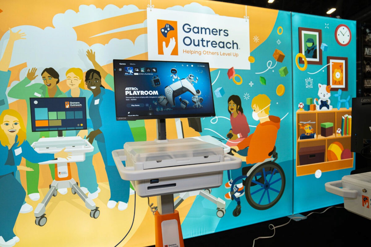 View of the main back panel of the Gamers Outreach booth. Highlighting a GO Kart delivery with happy hospital staff, and two kids playing on a GO Kart in a hospital playroom setting.