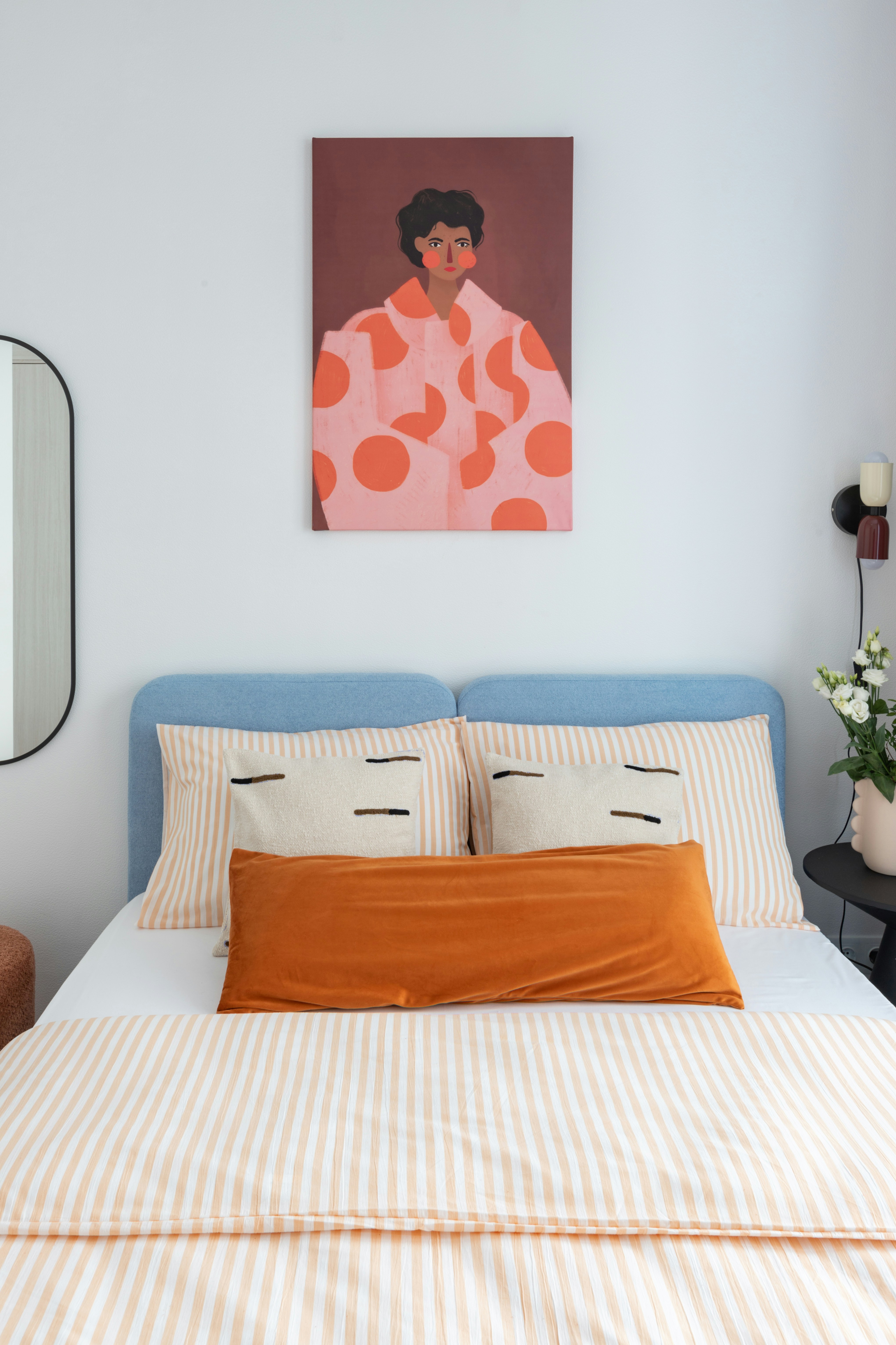A blue bed with striped bedding and decorative pillows.