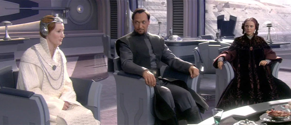 Mon Mothma, Bail Organa, and Padmé Amidala sit in a formal senate chamber, discussing the rising threat of the Galactic Empire in Revenge of the Sith.