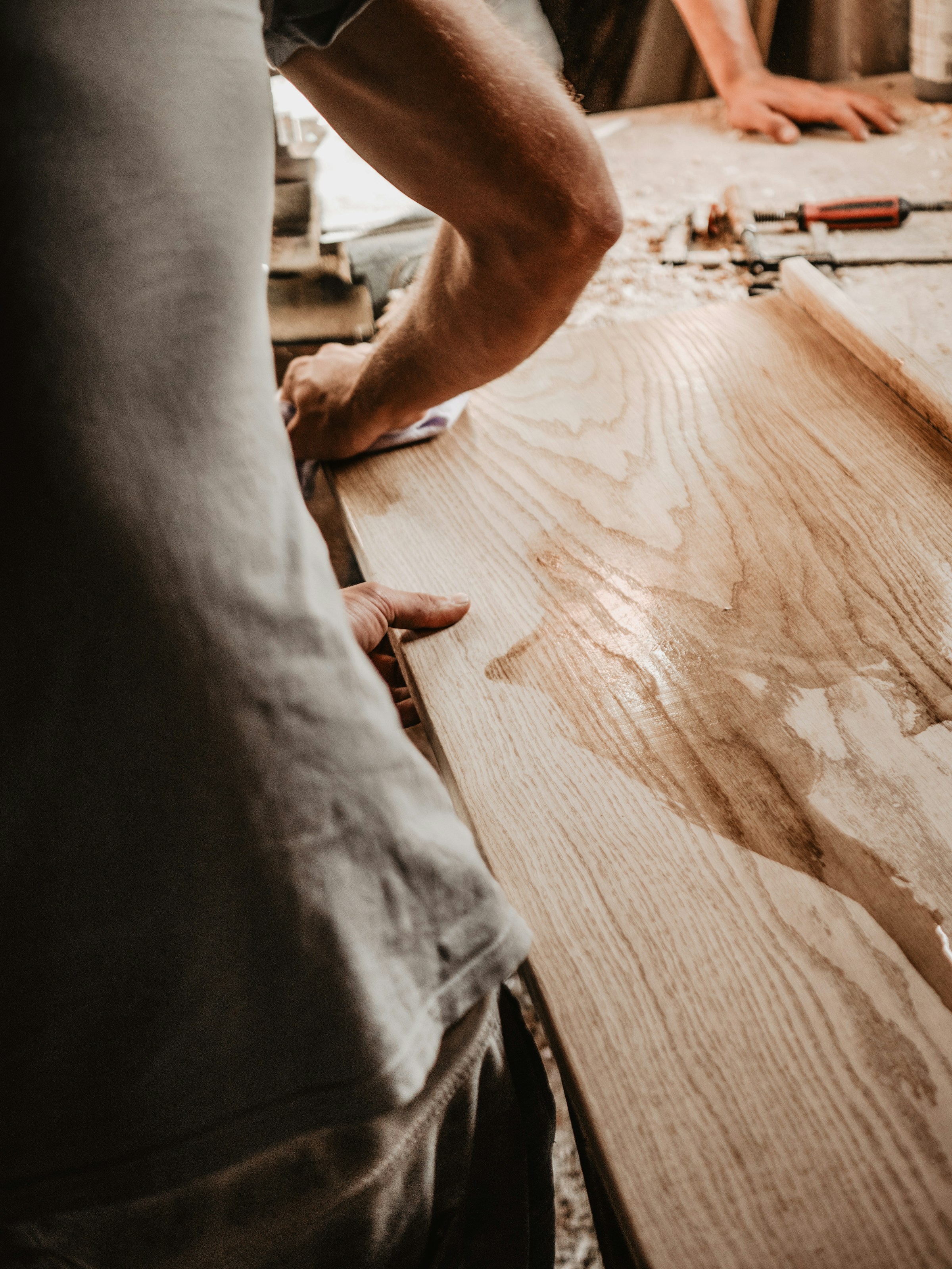 Hand wiping freshly stained wood after exterior fence staining in Ottawa.