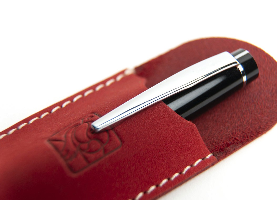 A black and silver pen partially inserted into the red leather sleeve, demonstrating the fit.