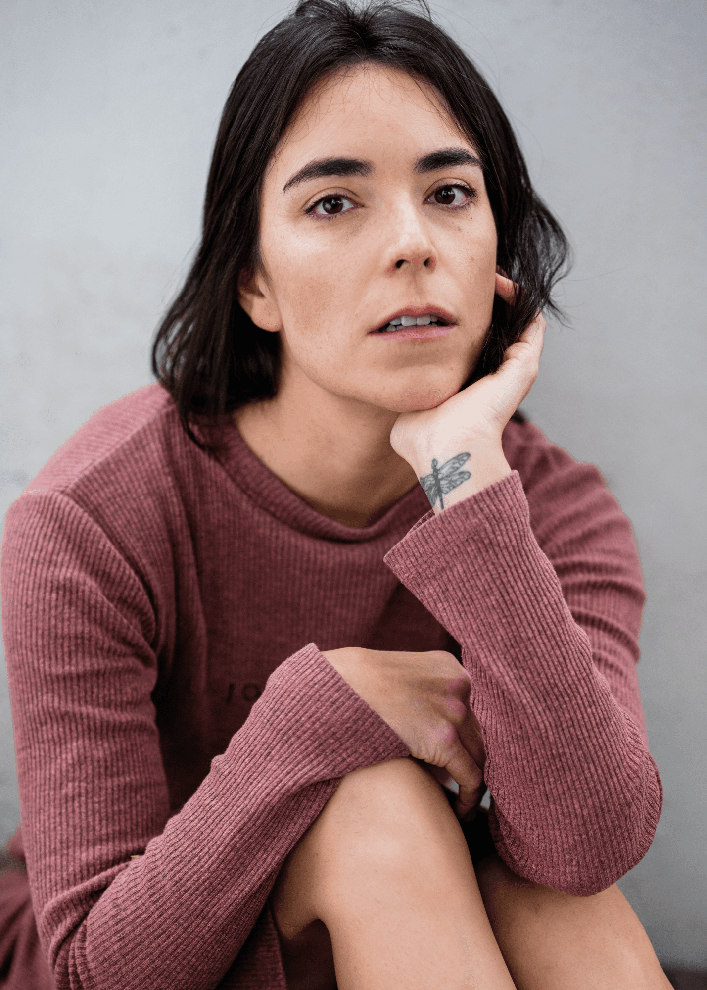 headshot casting photo of Raquel Violat Romero, actor, short dark-haired woman in burgundy sweater, pale background.