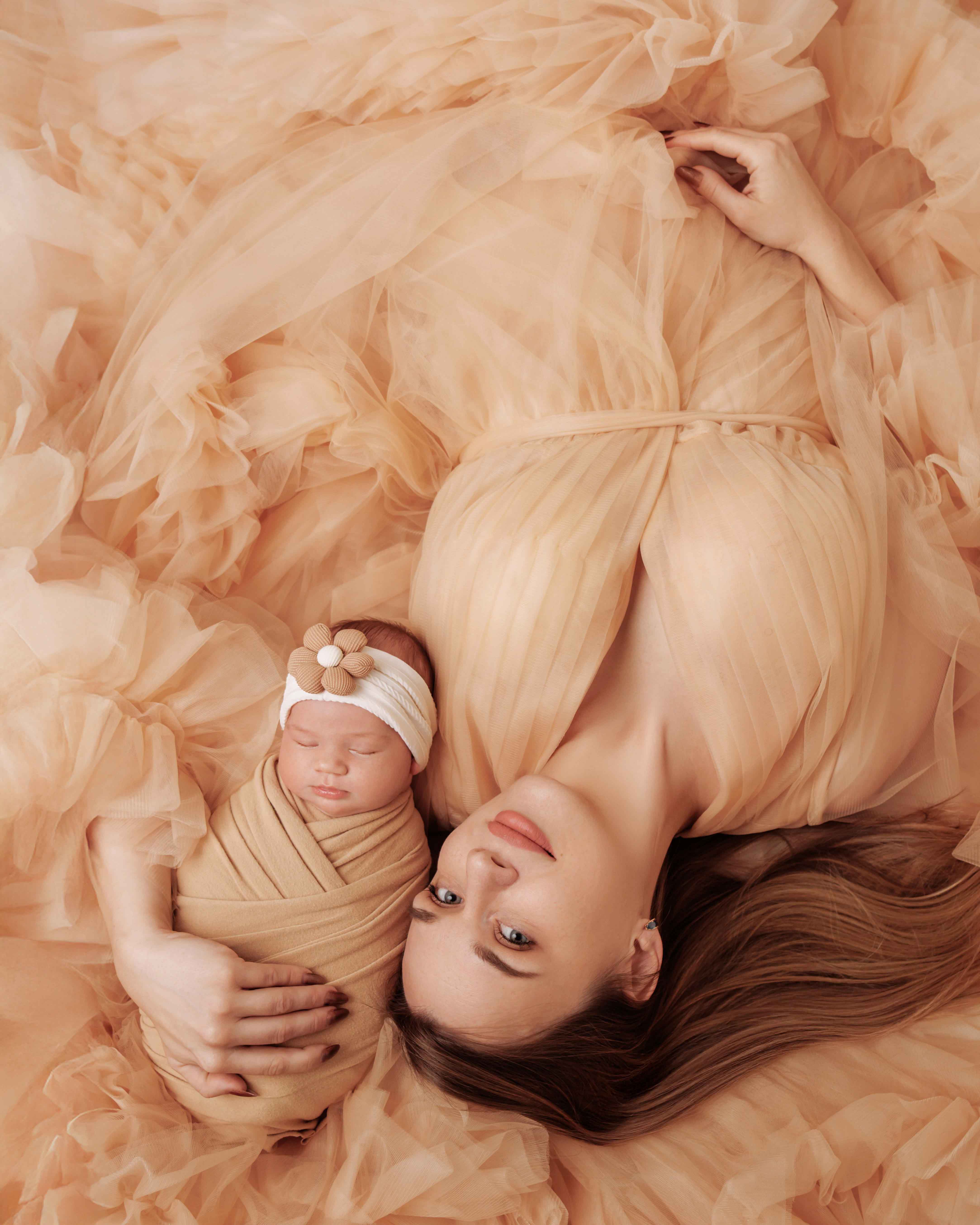 Tender newborn photo with mom — gentle embrace and warm connection