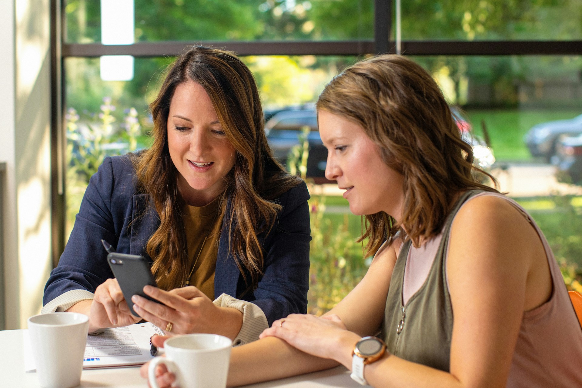 Sales women in meeting in cafe coffee shop holding phone