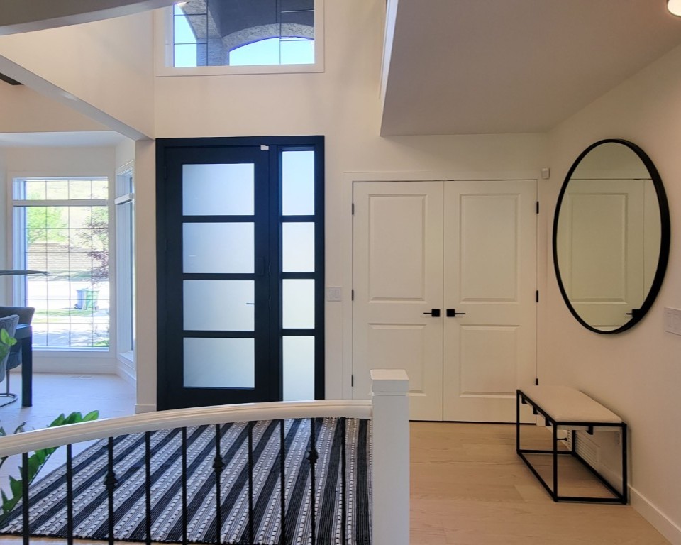 An entry way with a dark door with modern rectangular glass inserts and a white double door closet to the right.