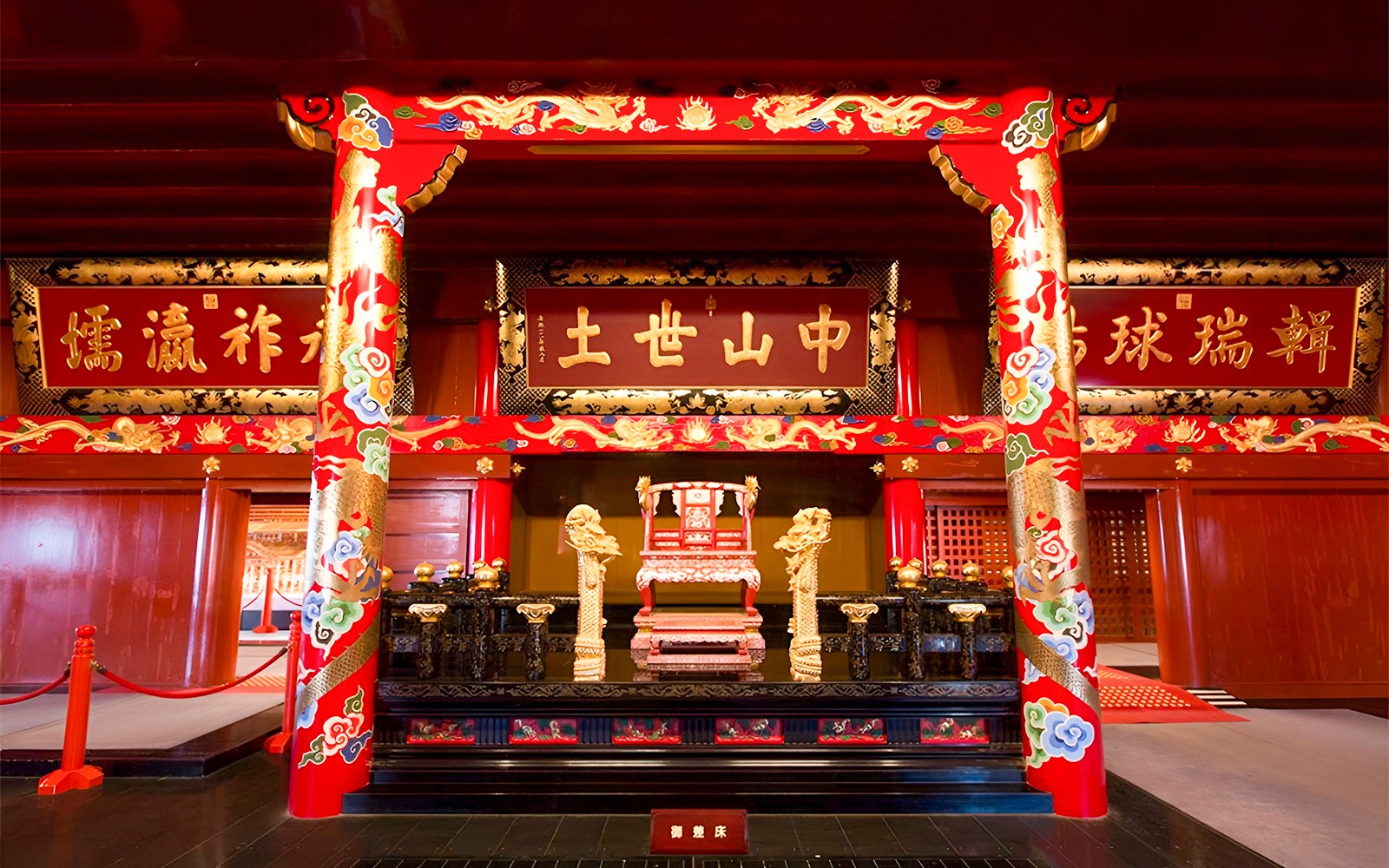 Interior of Okinawa Shurijo Castle Park with ornate red and gold throne and decorative pillars.