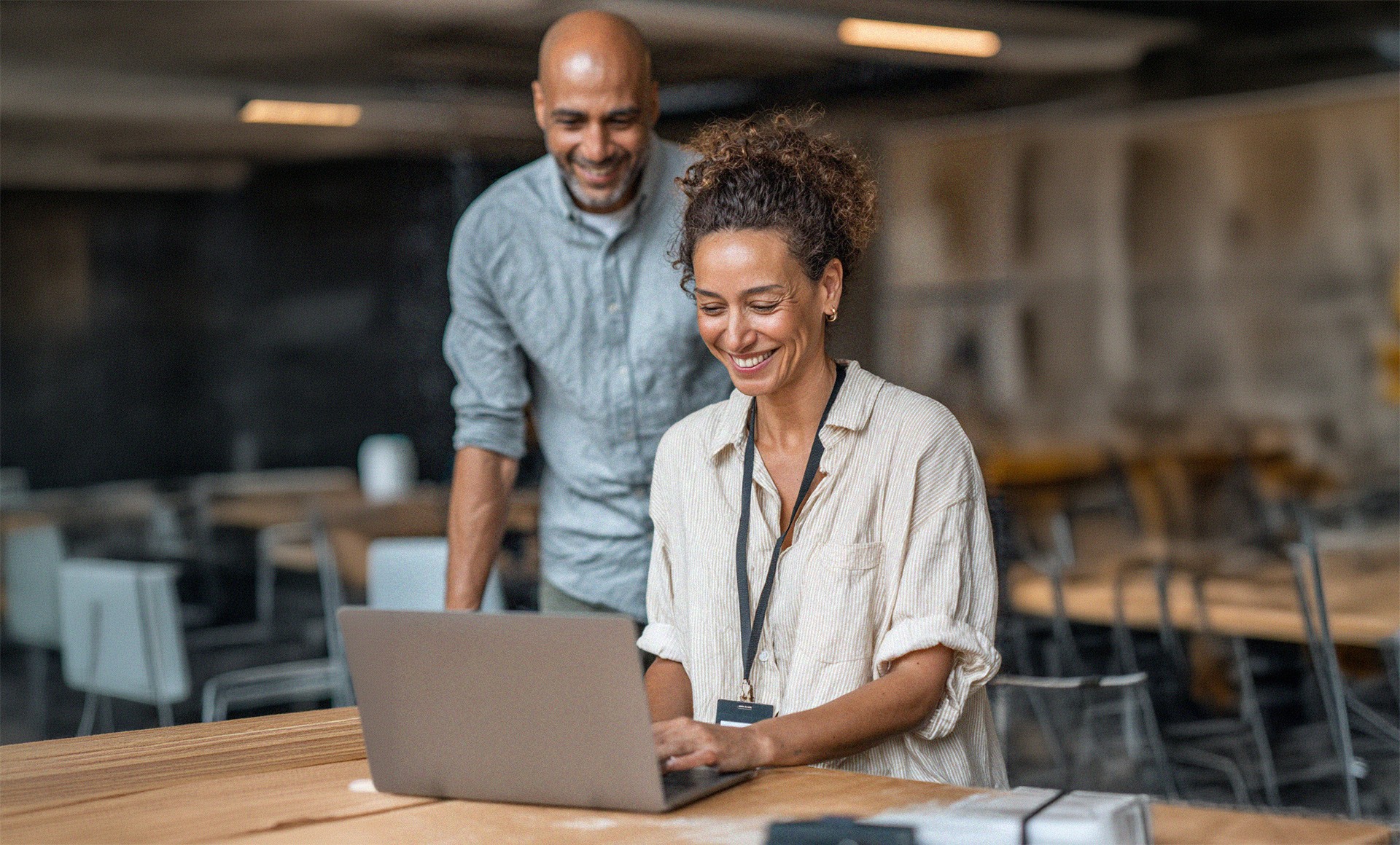 Two colleagues smiling while working together on a laptop in an office.