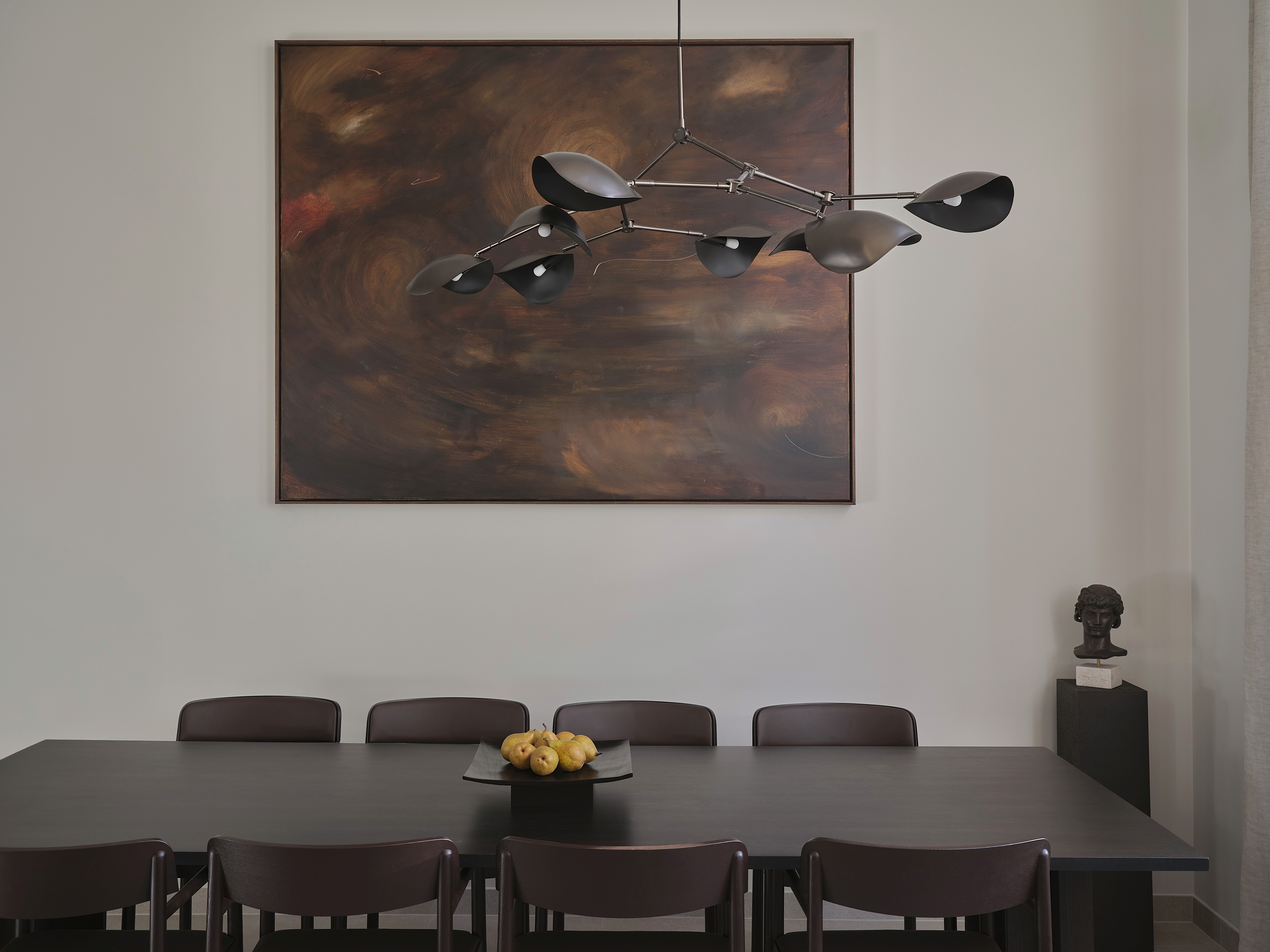 Dining room with black sculptural Serge Mouille-style chandelier, dark oak table, and large-scale abstract painting