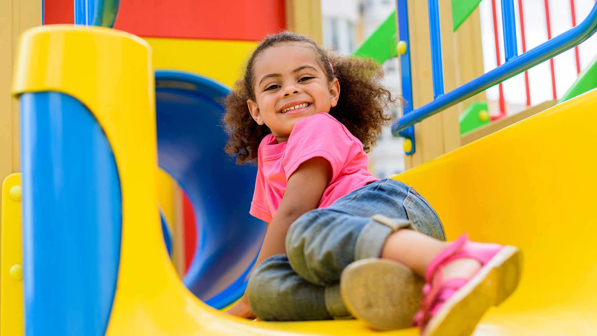 black girl on yellow playground slide