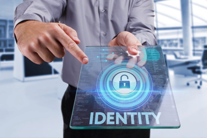 A person walks in front of large stone arches with dark doors, flanked by tall columns, in a historic building.