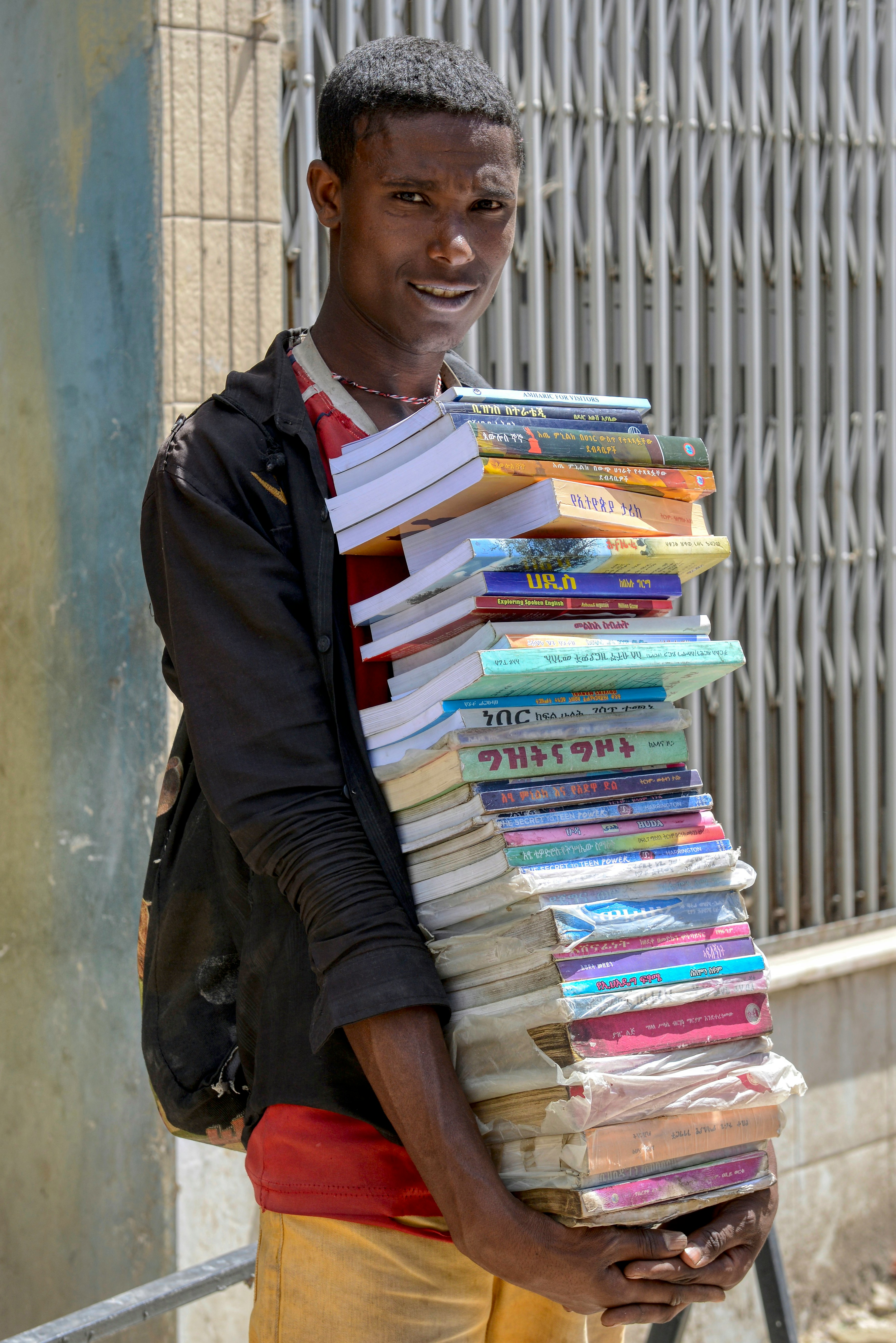 A man holding a large stack of books