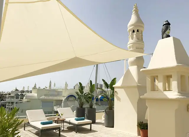 atico con vela de sombra crema sobre el mar