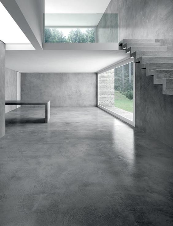 Modern concrete interior with large windows and stairs.