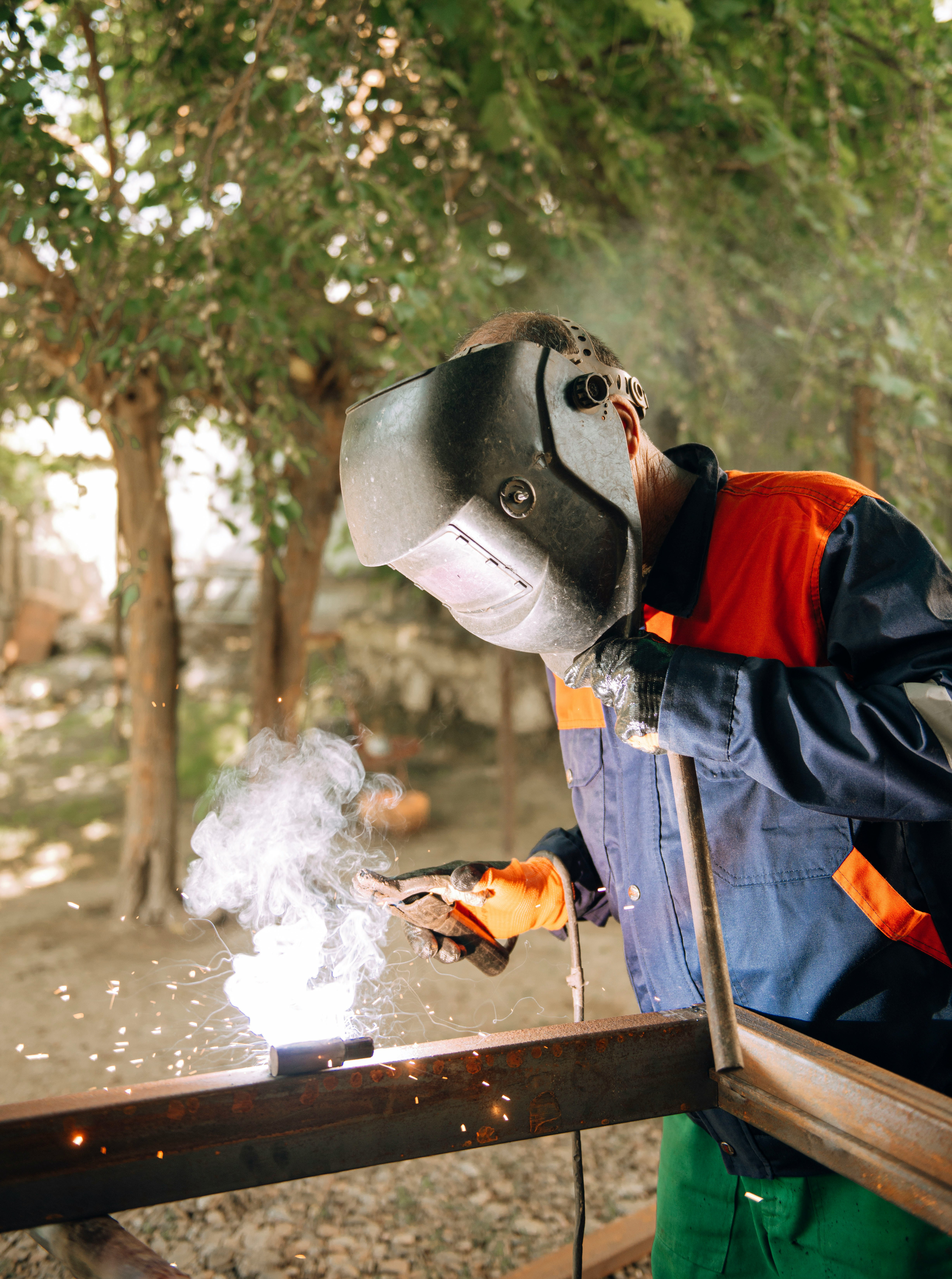 a man welding a piece of metal in a forest