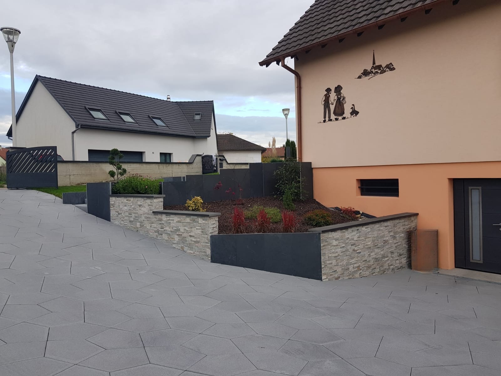 Aménagement extérieur avec murets en pierre et dallage béton réalisé par Acqua Terra dans le Haut-Rhin