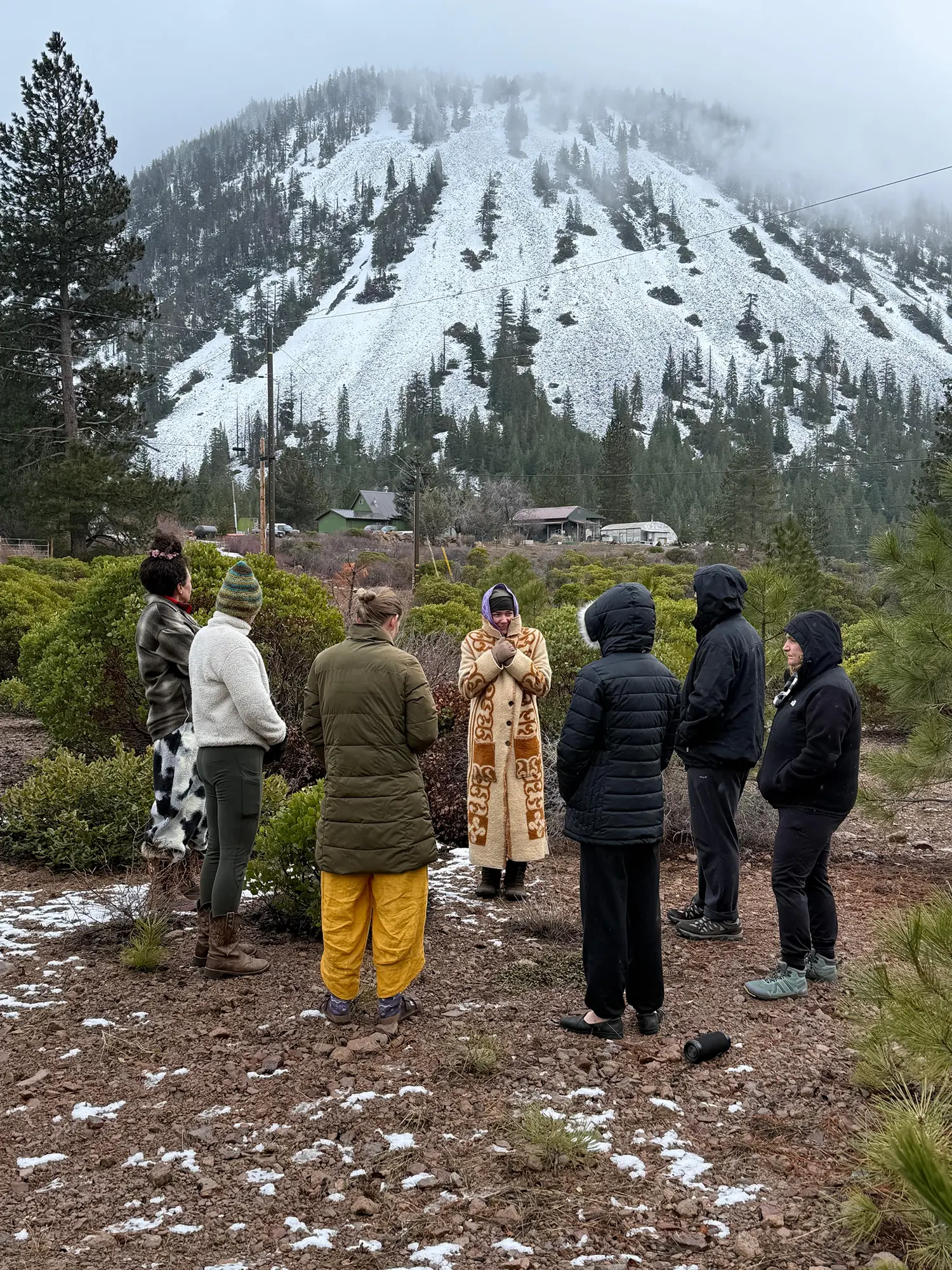 Small group of retreat participants gathered in circle on a snowy mountain landscape