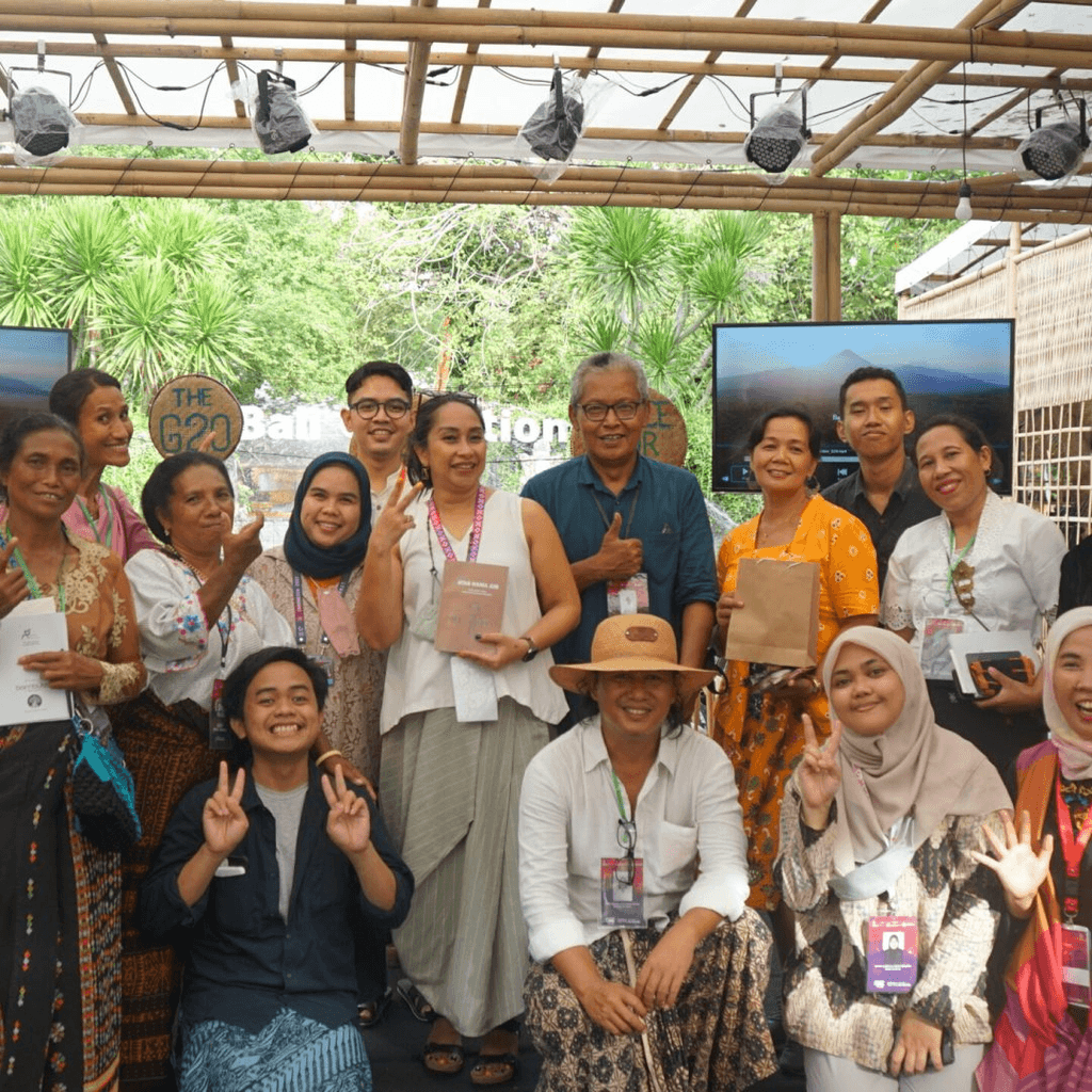 Smiling young man with short hair poses against a dark background, wearing a green button-up shirt.