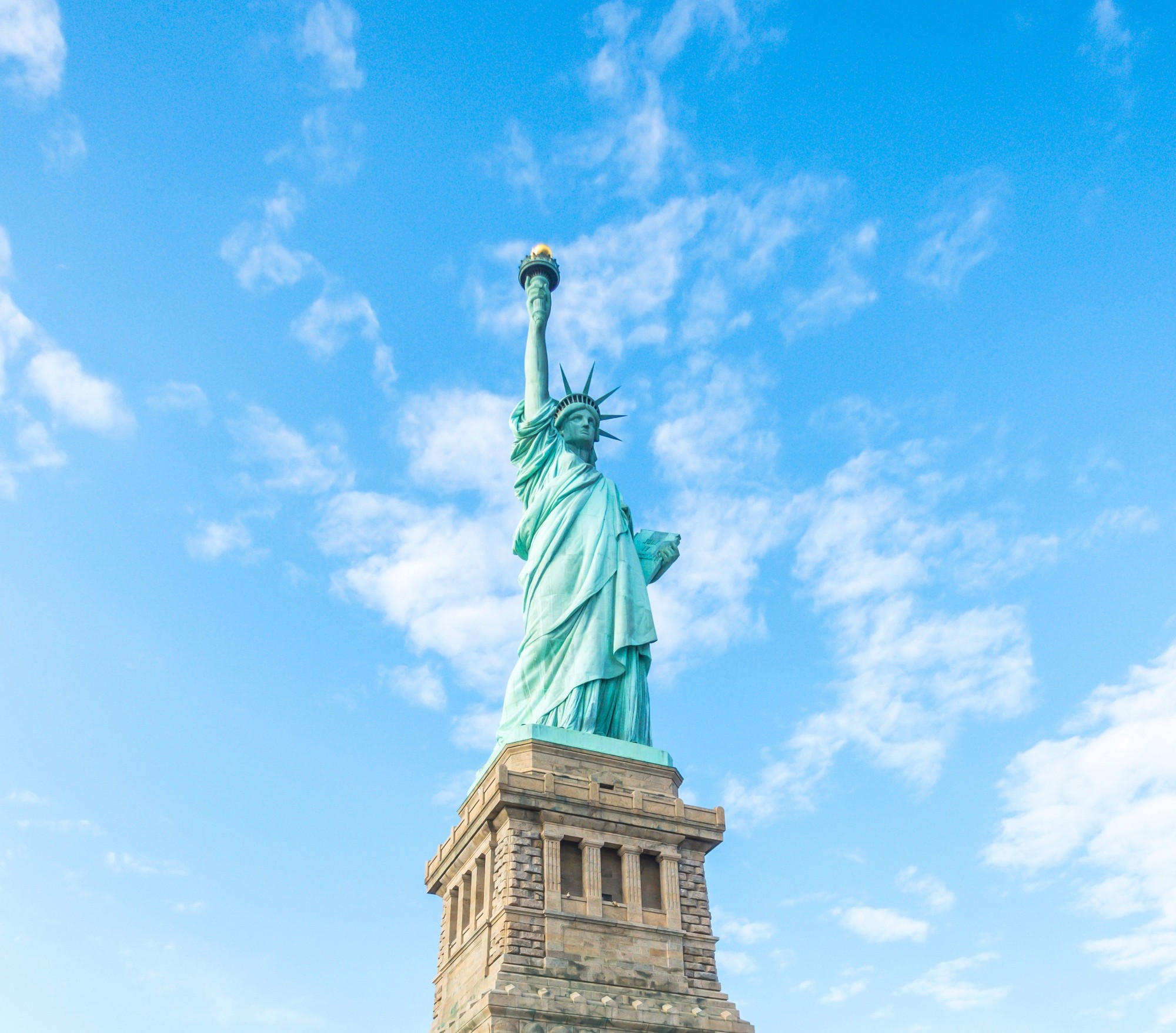 Statue of Liberty, New York under white and blue cloudy skies