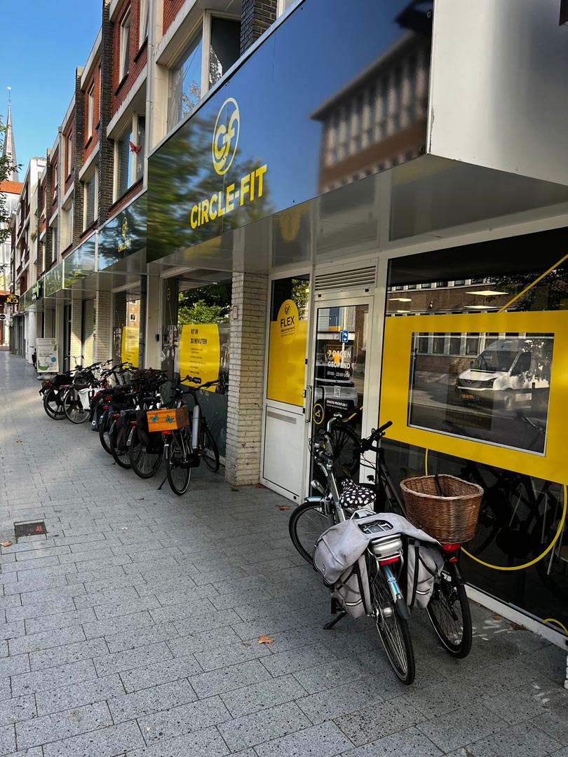 A brightly colored Circle Fit hub exterior with outdoor seating and a small cart on the sidewalk.