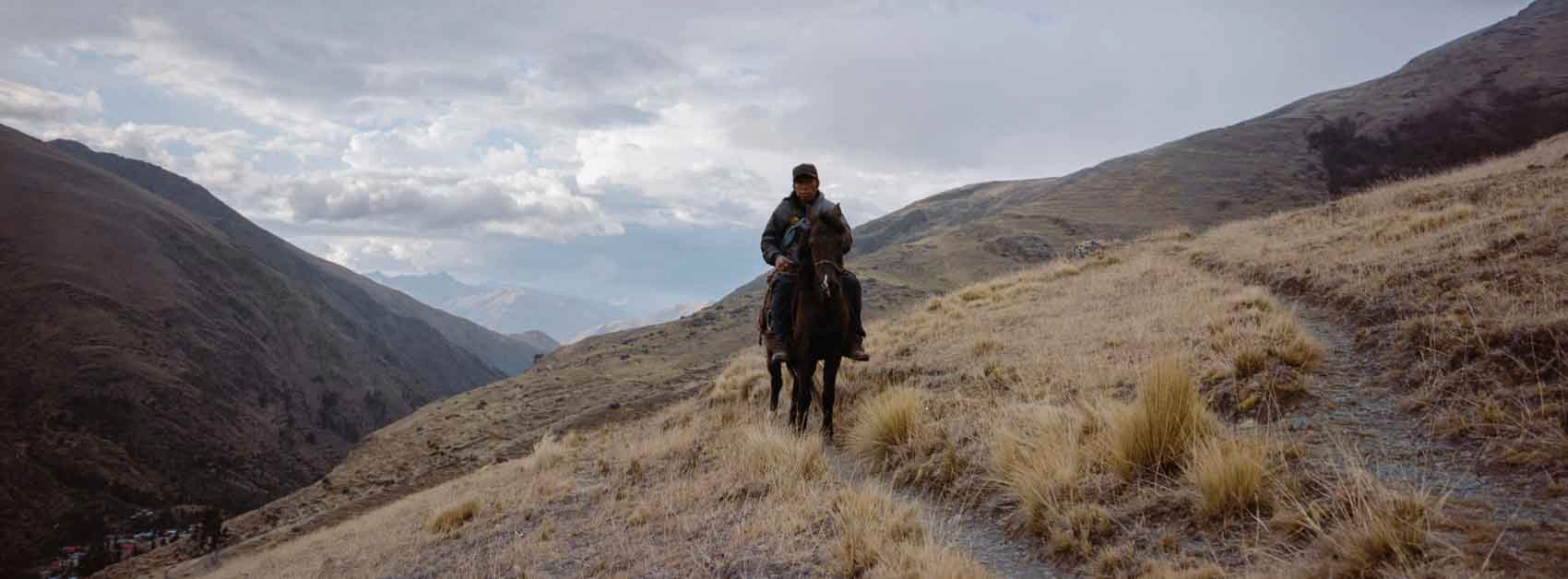 Panoramic film photograph taken near Machu Picchu elevation, showing a local riding his horse in the Andean mountains, highlighting everyday life at high altitude.