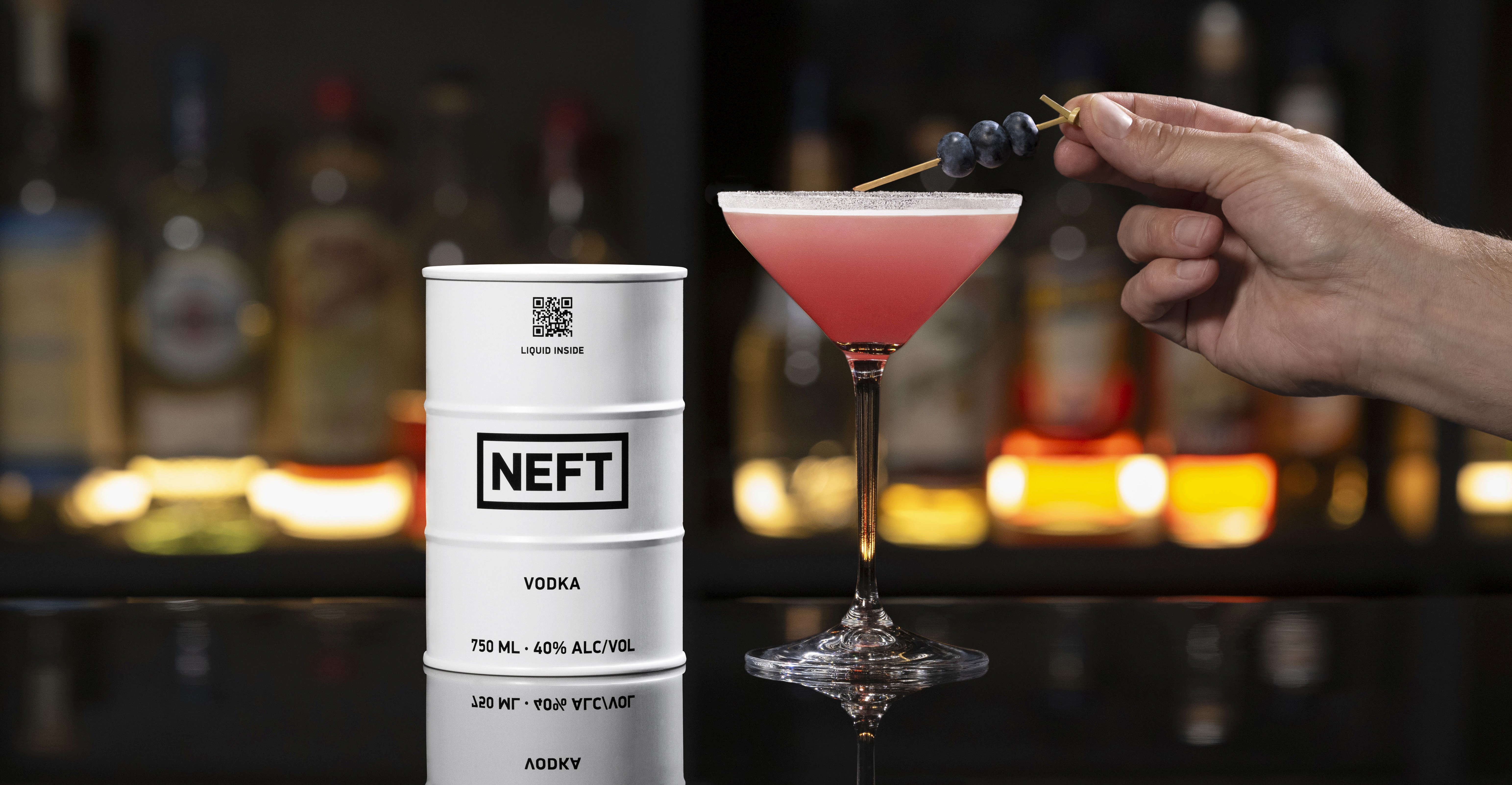 A NEFT Barrel and a glass of Blueberry Lemon Drop on a bar counter.