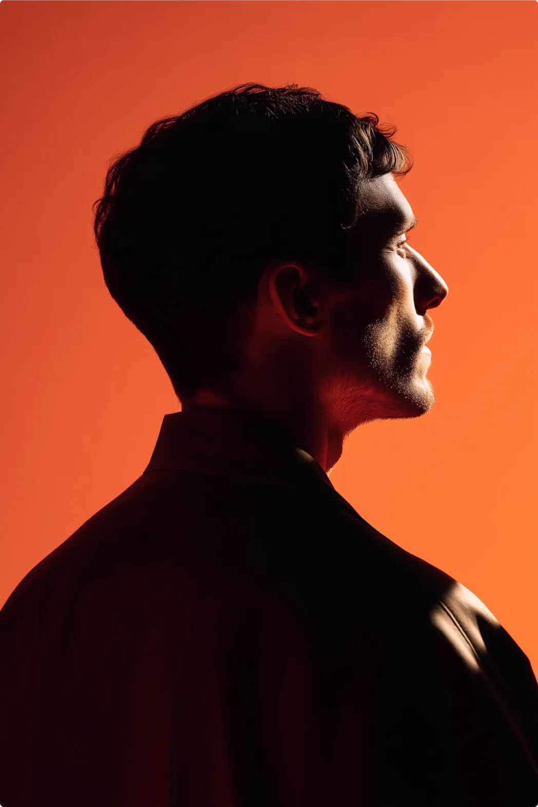 A man’s profile against an orange background.