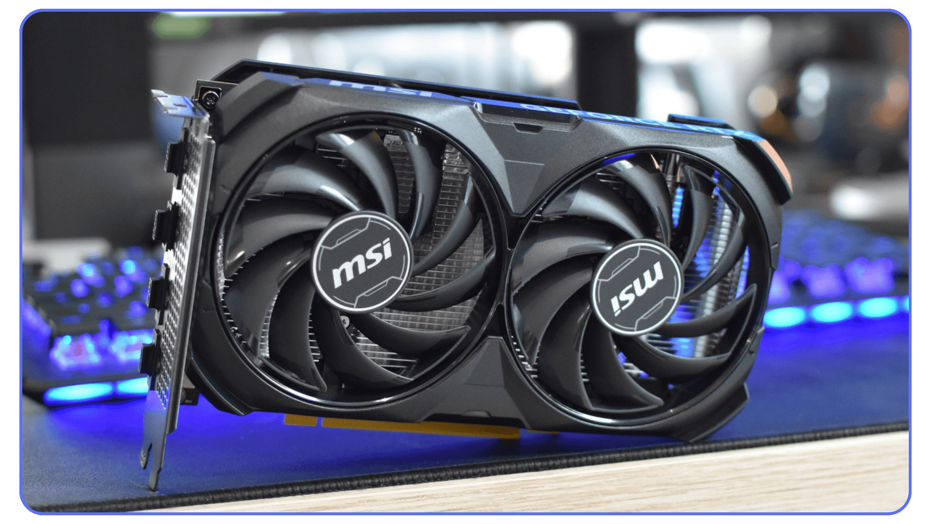 A close-up shot of an MSI graphics card with dual cooling fans, placed on a dark surface with blue lighting.