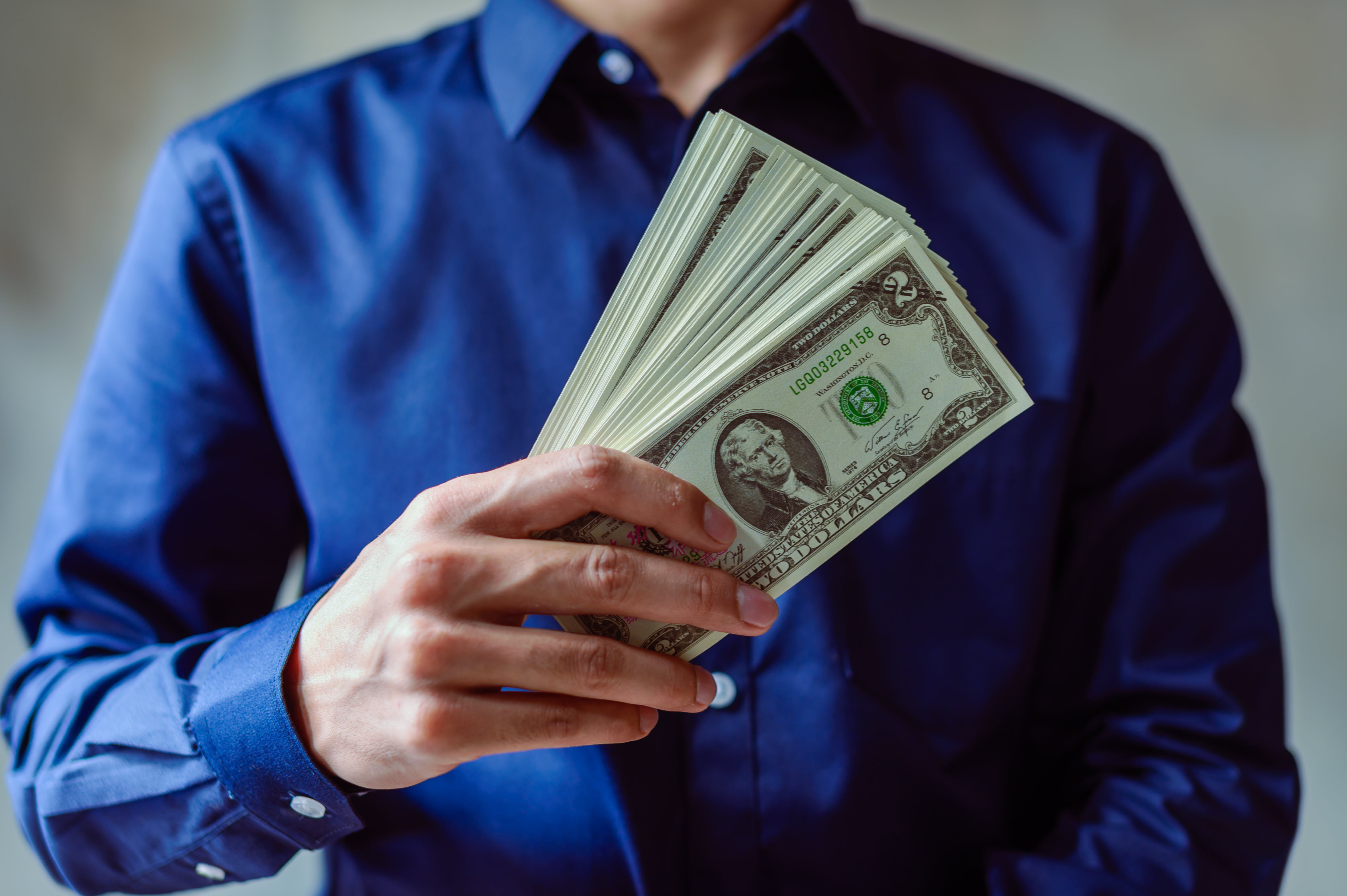 Person holding dollars to pay closing costs