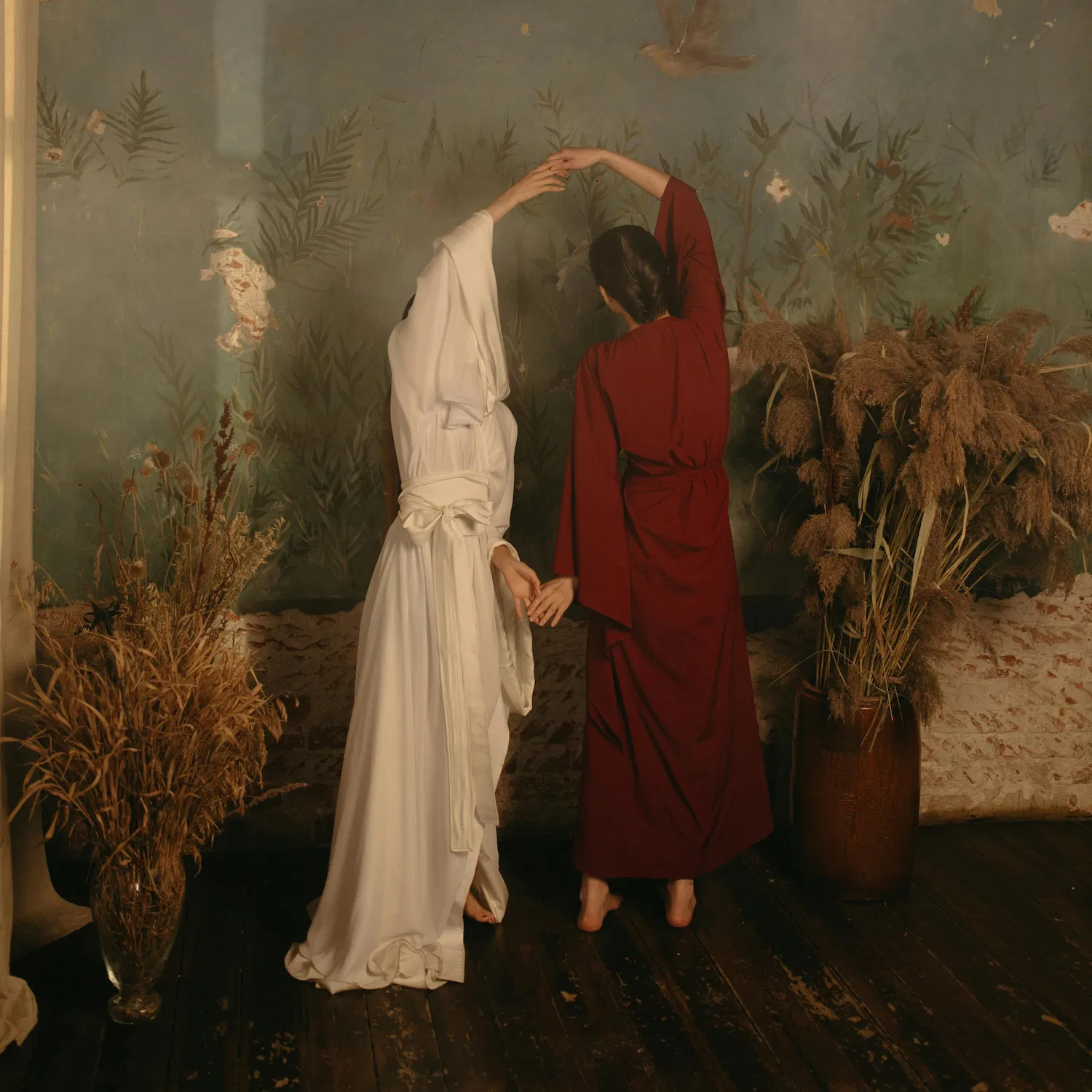 Two women in flowing robes hold hands and dance gracefully indoors, symbolizing bisexual and pansexual affirming therapy in NYC.