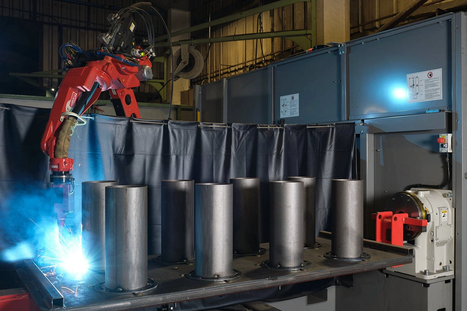Robotic laser welding process joining steel components, with a focused welding head producing sparks during precision fabrication.