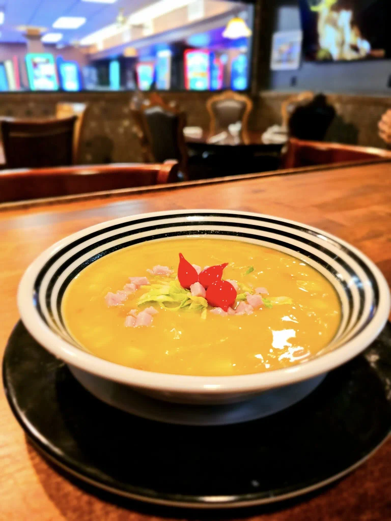 A hearty bowl of soup served on a rustic wooden table at Dueling Pistols Restaurant.