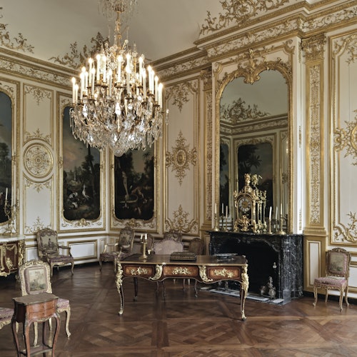 装饰华丽的房间,配有大型吊灯、古典家具、镀金镜子和装饰性壁画。