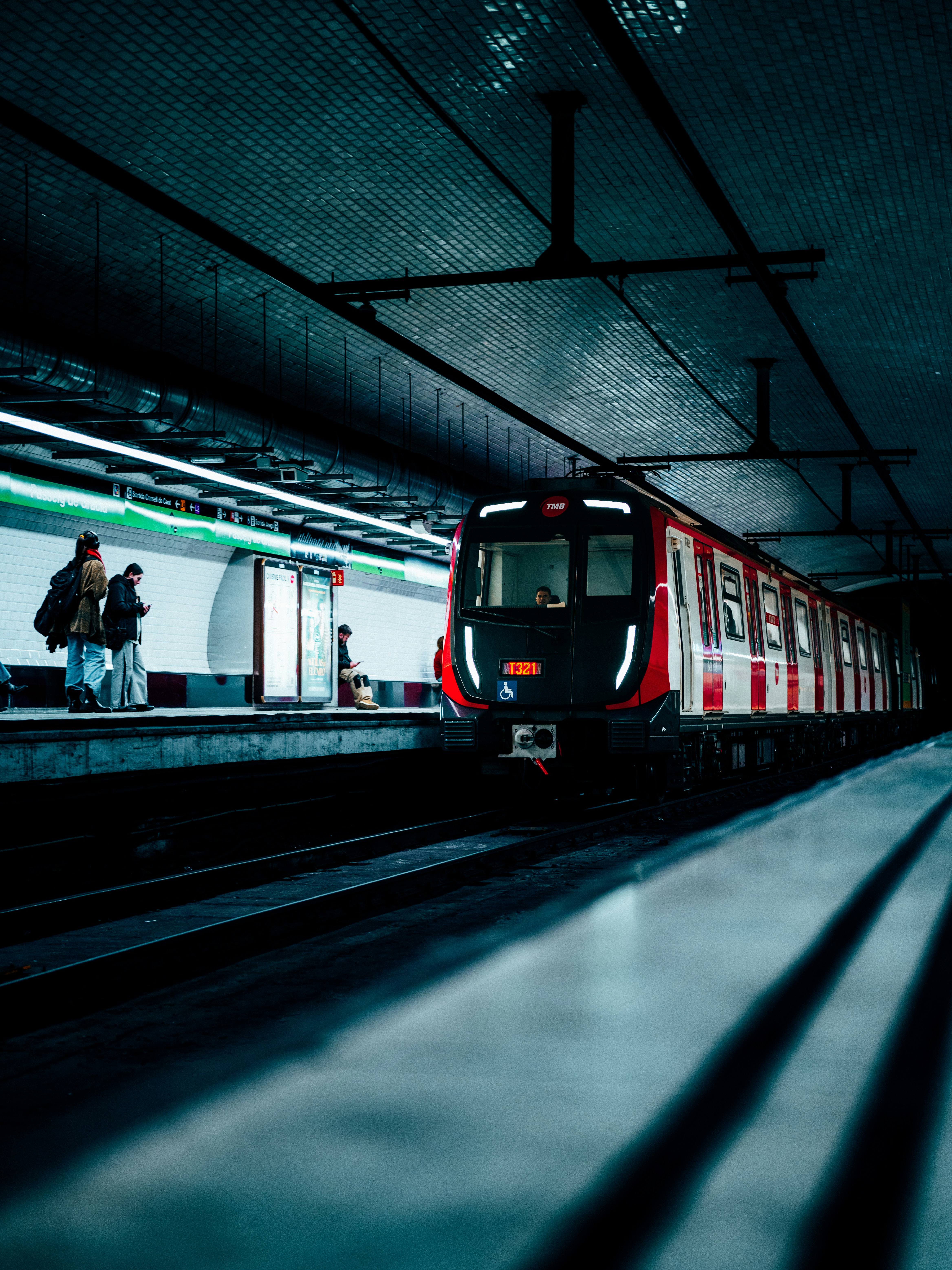 A train waits at a dark subway station platform.