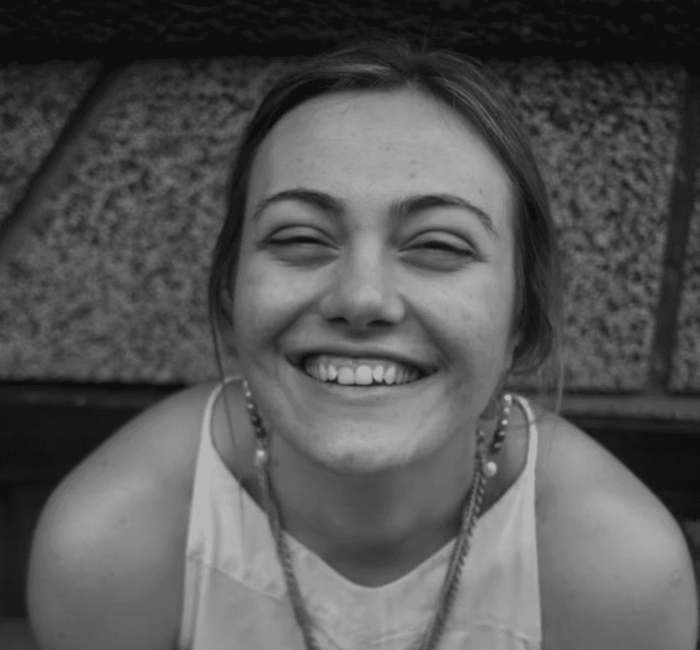 a young man wearing glasses standing in front of a mountain