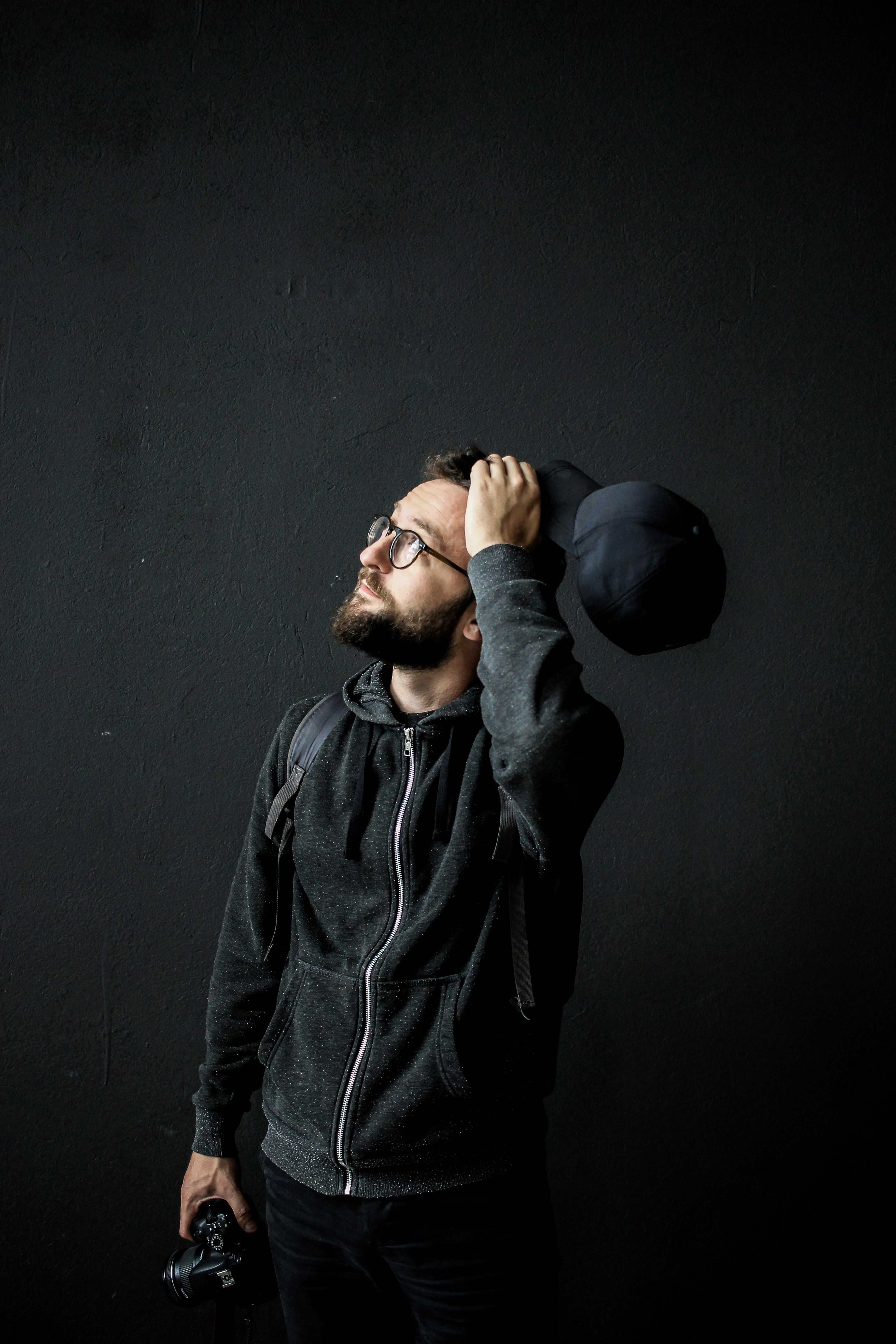 man holding a hat as he scratches his head