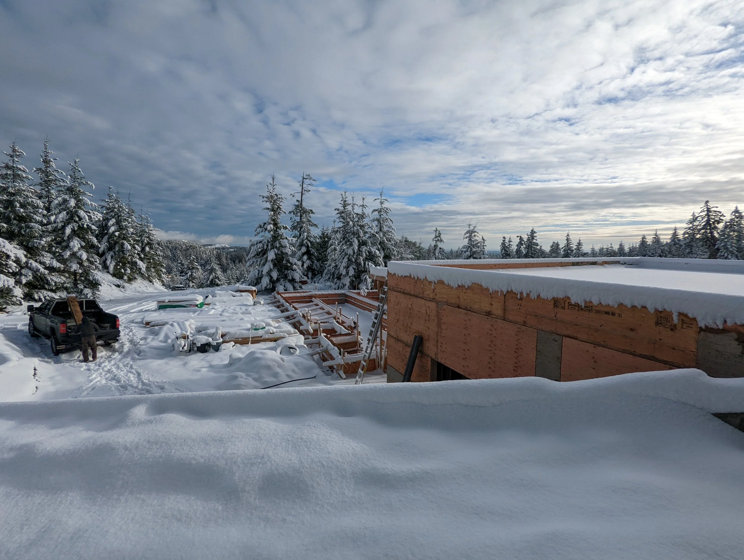 Modern two-story home with large glass windows, warmly lit interiors, and a balcony. Surrounded by trees and a manicured lawn at dusk. Cozy ambiance.