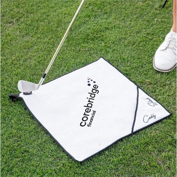 A golf towel on the green with a golf club over the towel.
