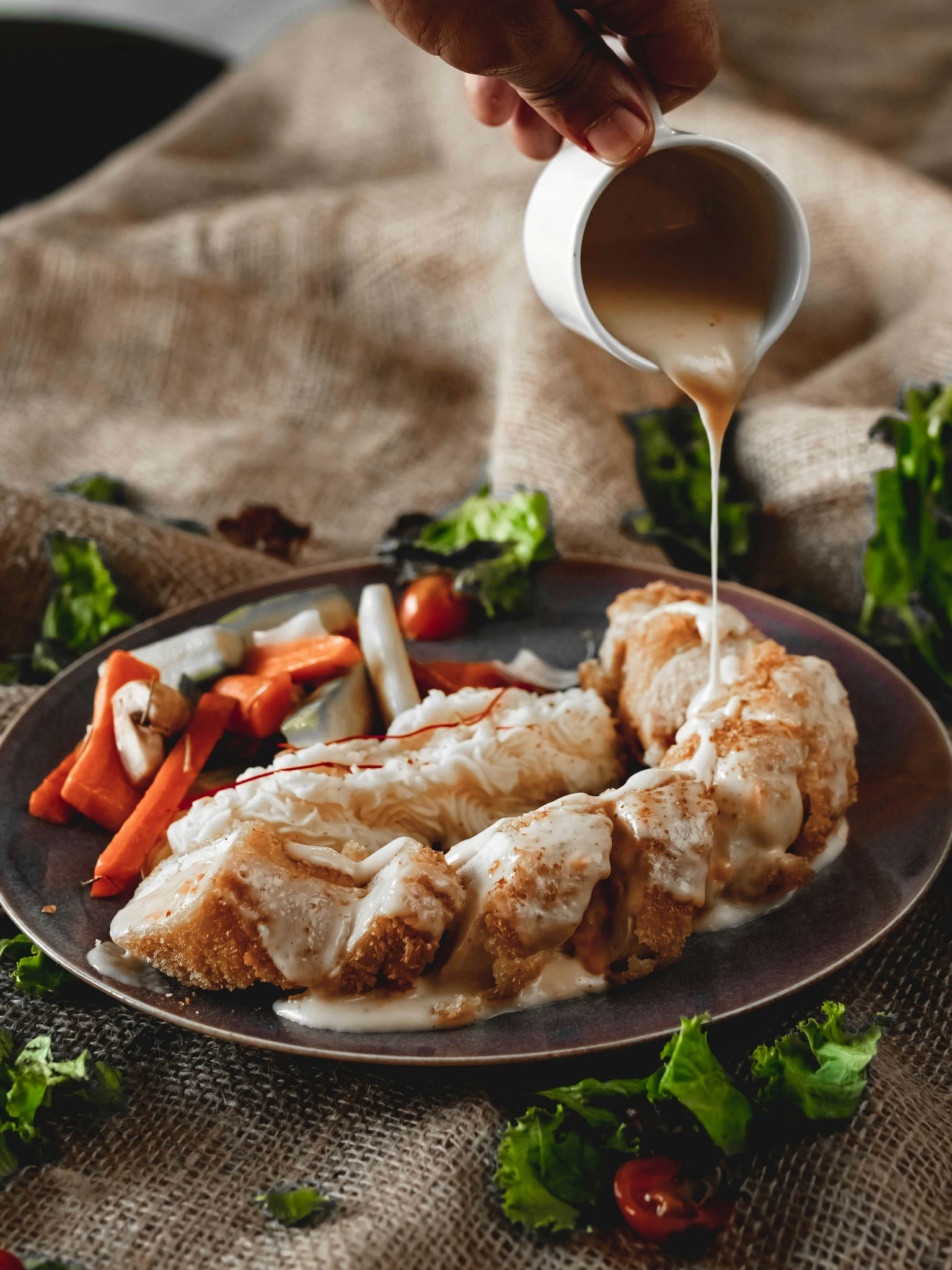 Sauce being poured over a dish with vegetables.