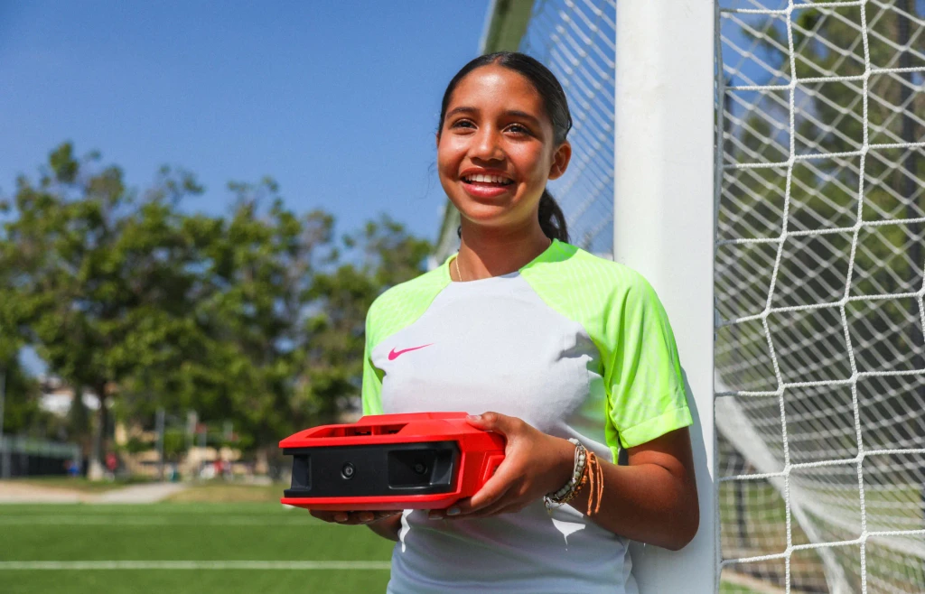 Youth soccer player smiling while holding a Reeplayer camera