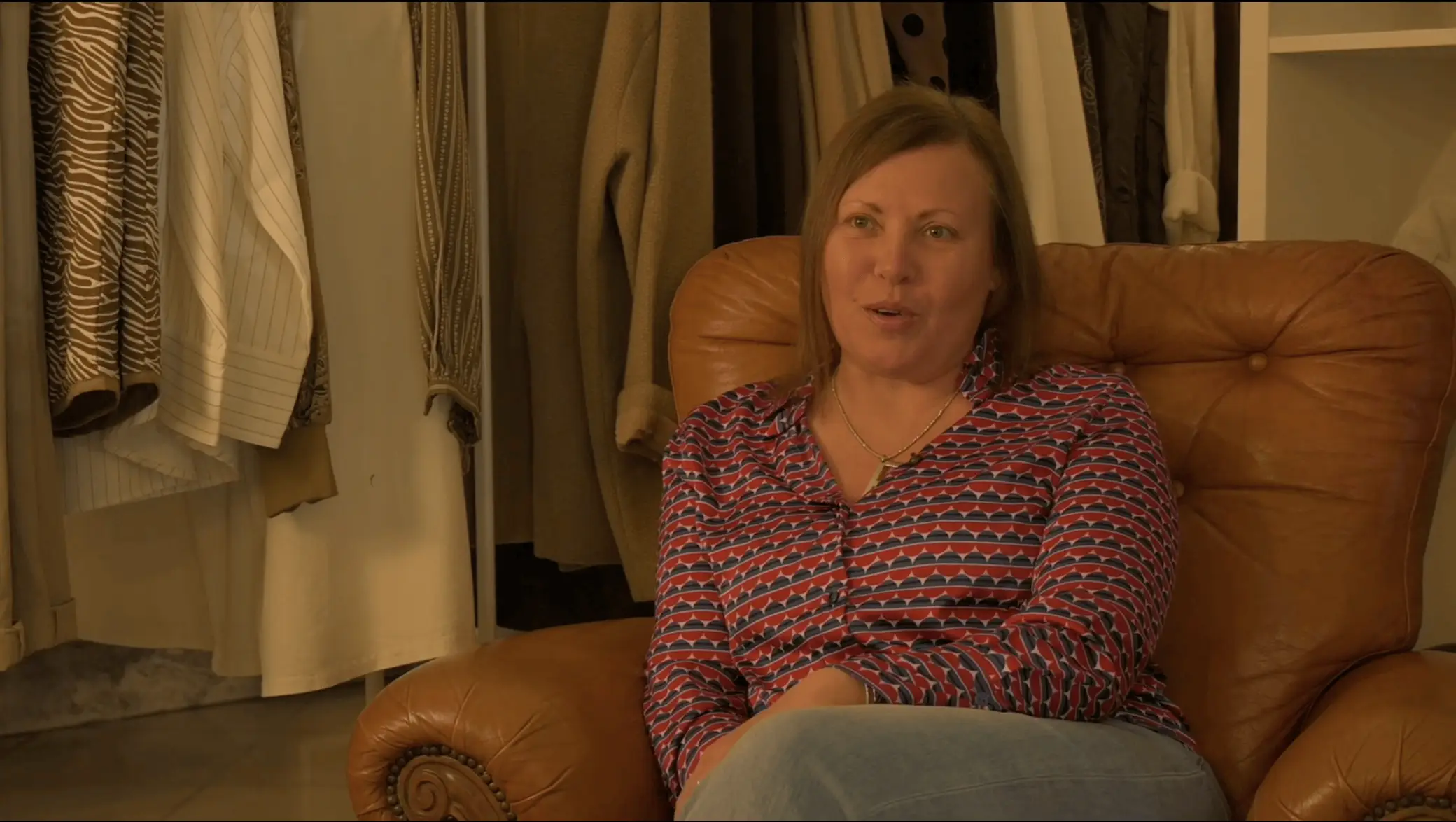 Donna seduta su una poltrona in pelle dentro un negozio di abbigliamento mentre viene intervistata per il documentario donne in bilico