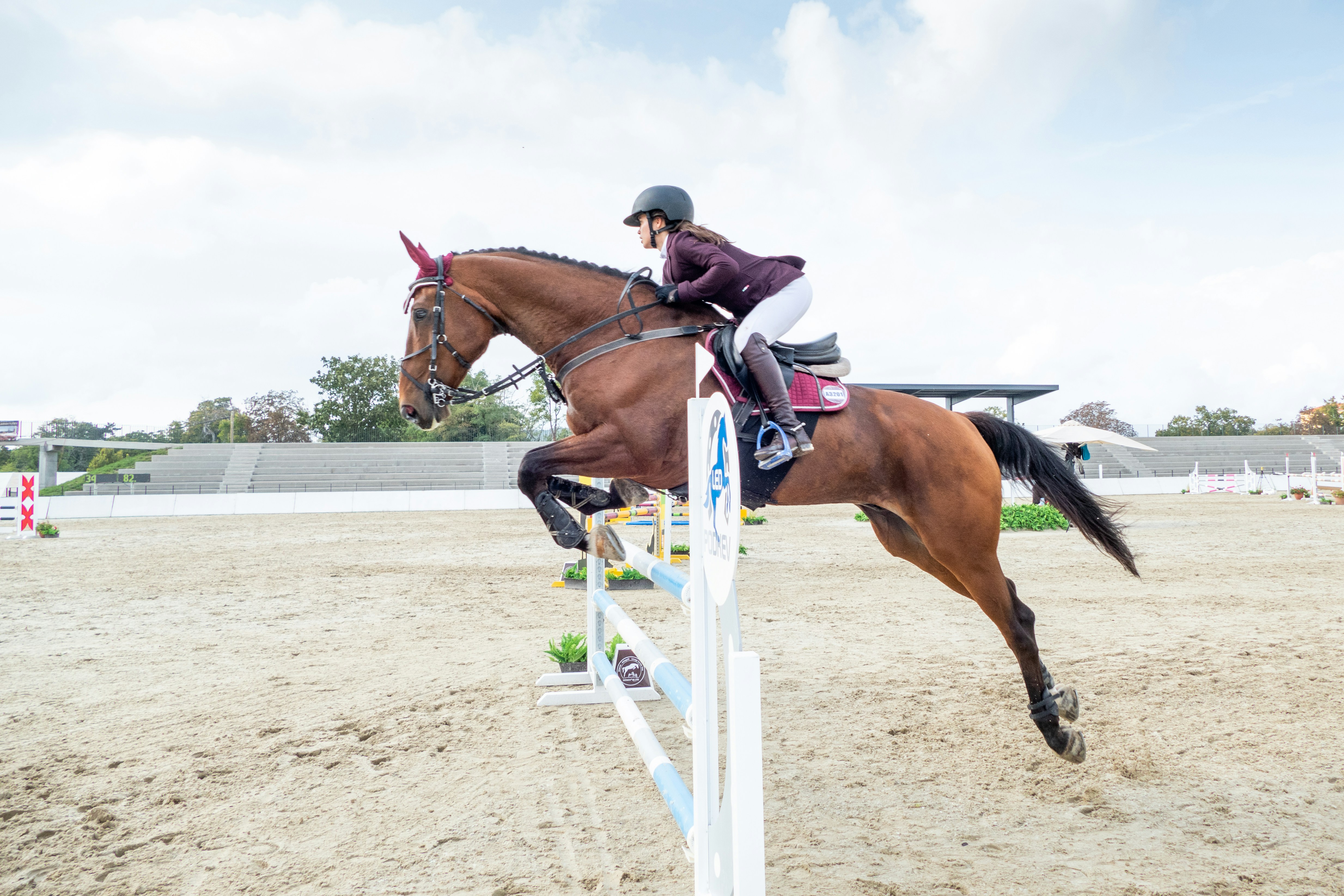 A rider jumping a white vertical in the main ring