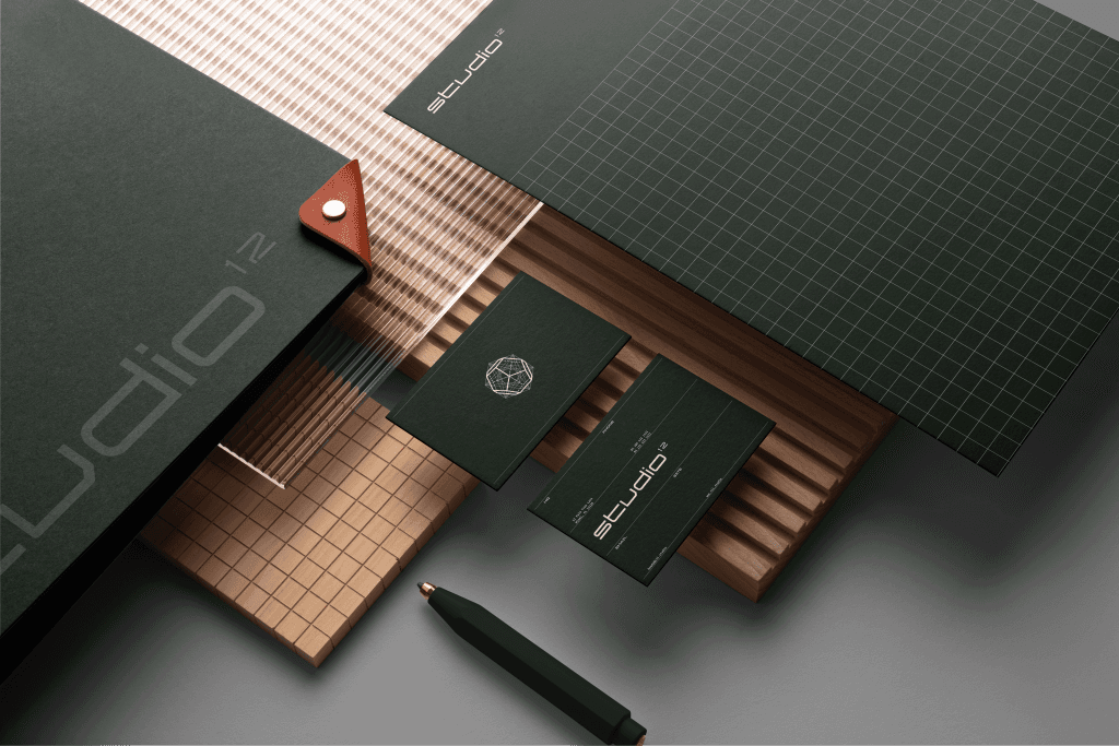 A mockup of Studio¹² stationary, featuring a folder, pen, business cards, and letterhead