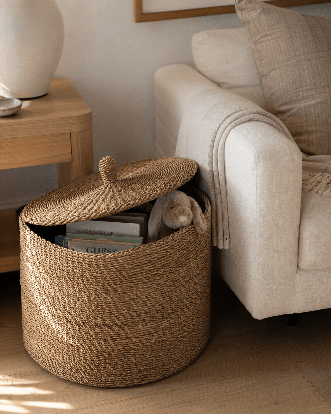Woven basked in a living room with books and a stuffed bunny stored inside.