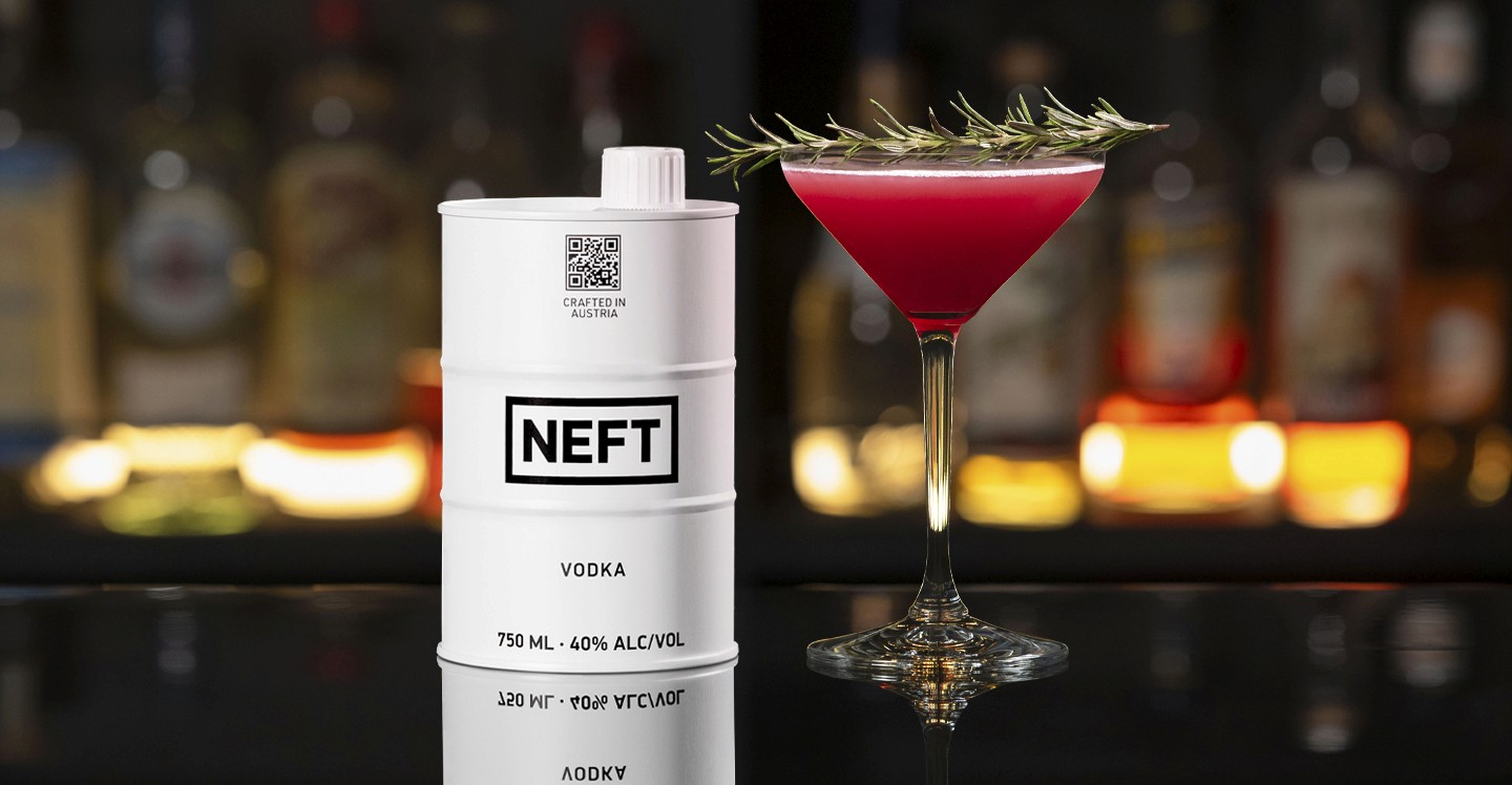 A NEFT Barrel and a glass of Pomegranate Bliss Martini on a bar counter.