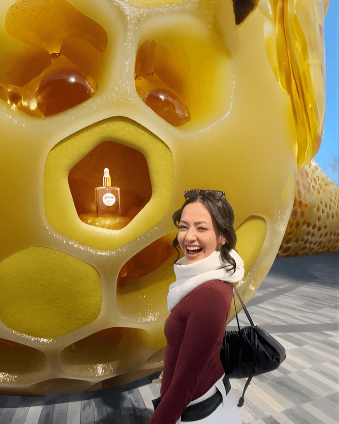A close-up mixed-reality shot shows the woman laughing next to a Gisou product displayed in a golden hexagonal cell
