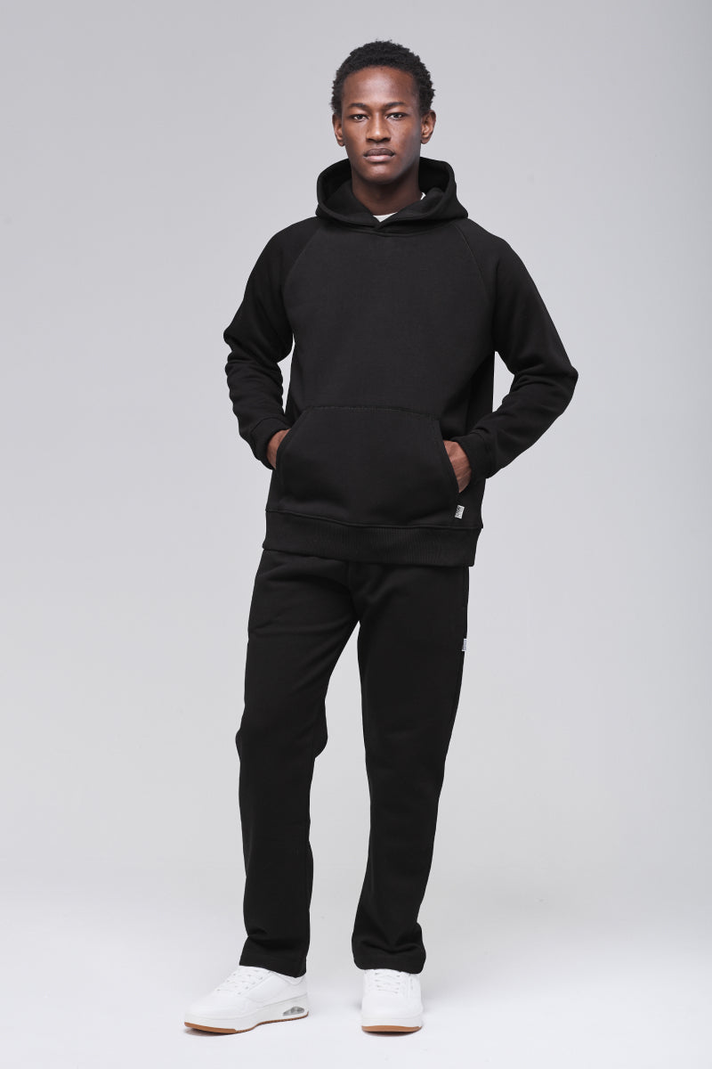 Front view, classic hoodie in heavyweight cotton blend, model hands in front pocket and looking in camera