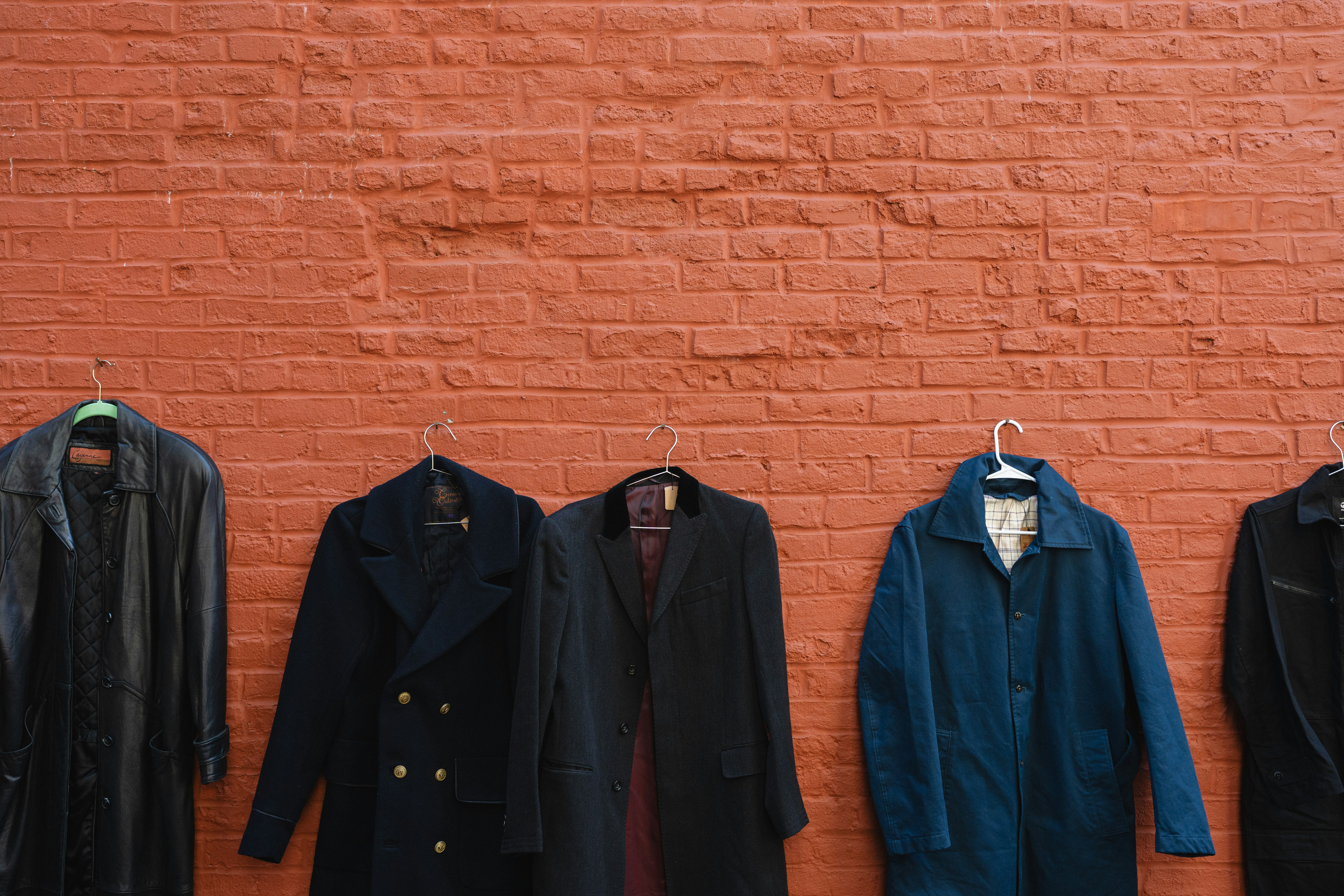 Five coats hanging on a brick wall